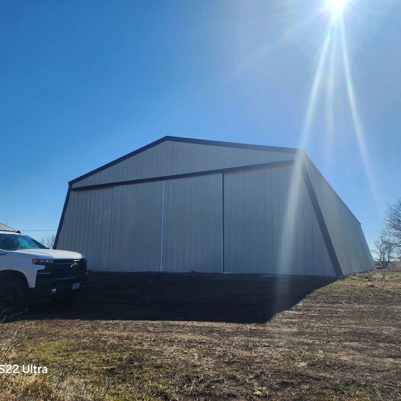 A white truck is parked in front of a large white building.