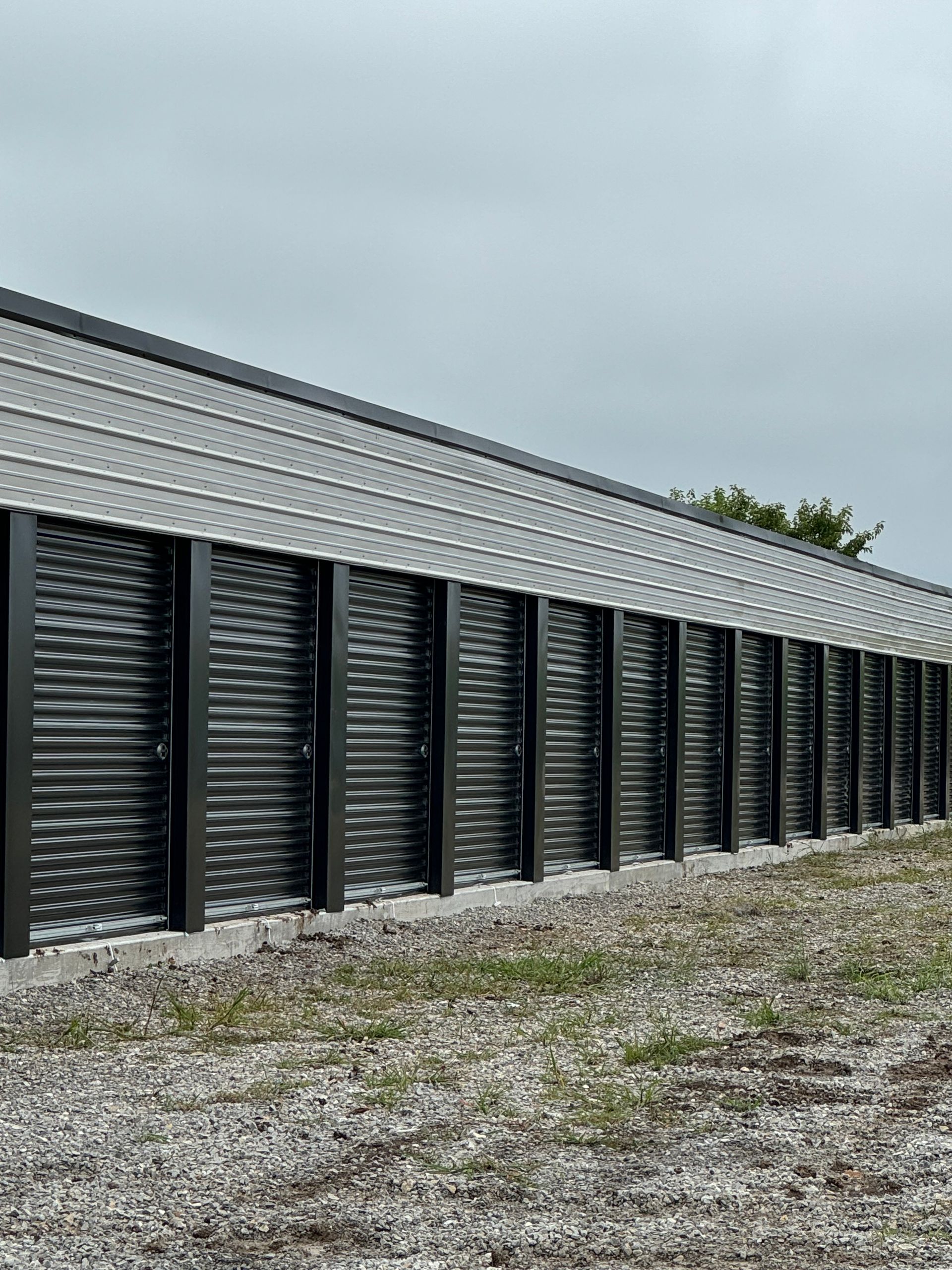 A row of black garage doors are lined up in front of a building.