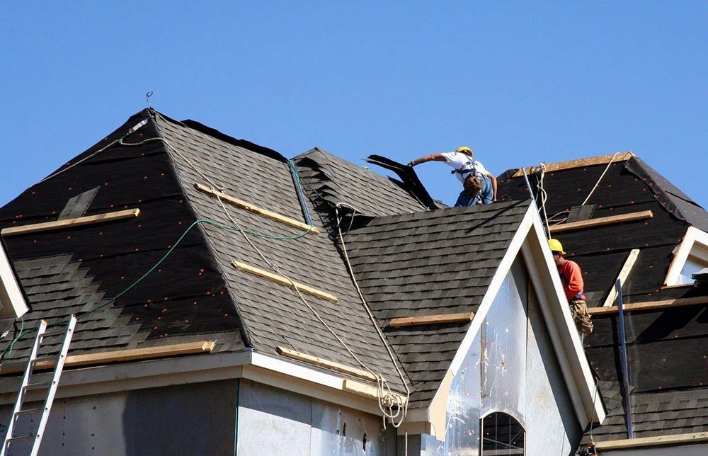 Two men are working on the roof of a house.