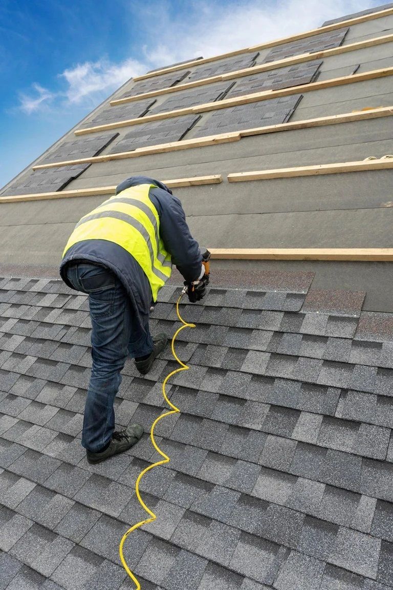 A man is working on a roof with a tape measure.