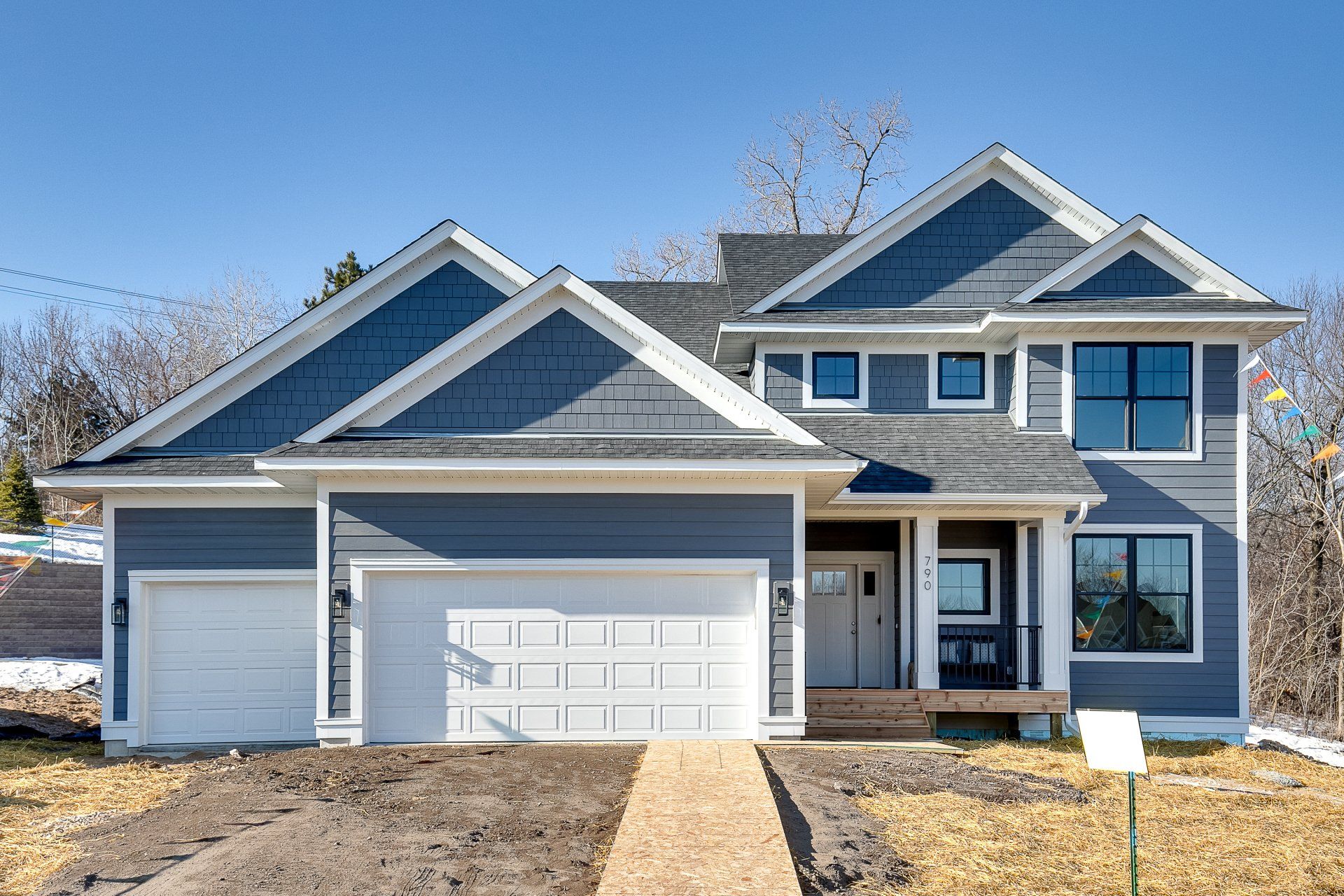 A large blue house with a white garage door is for sale.