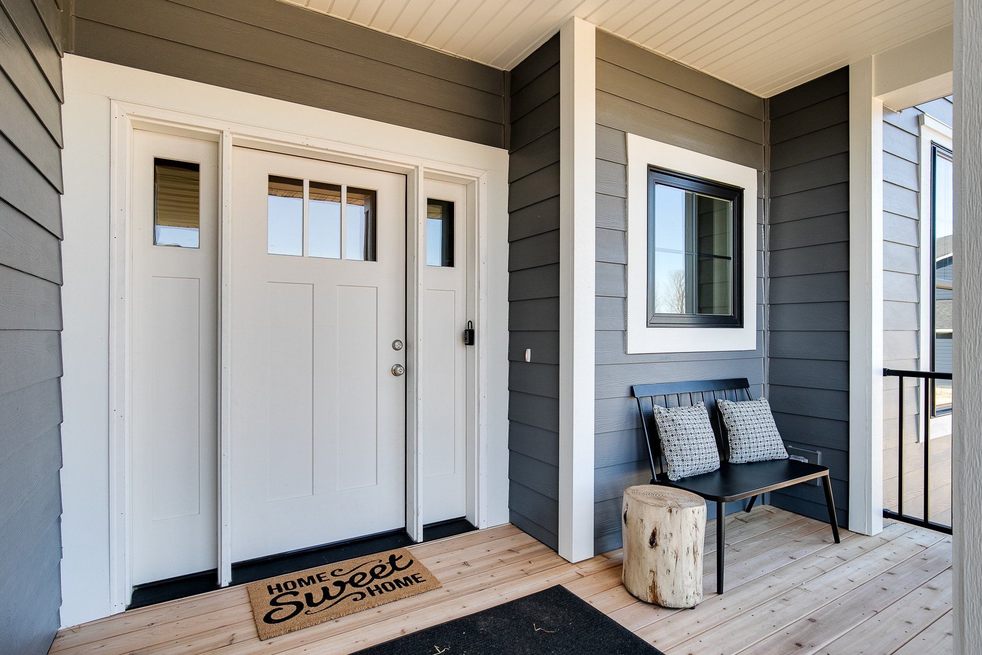 A porch with a bench and a welcome mat on it