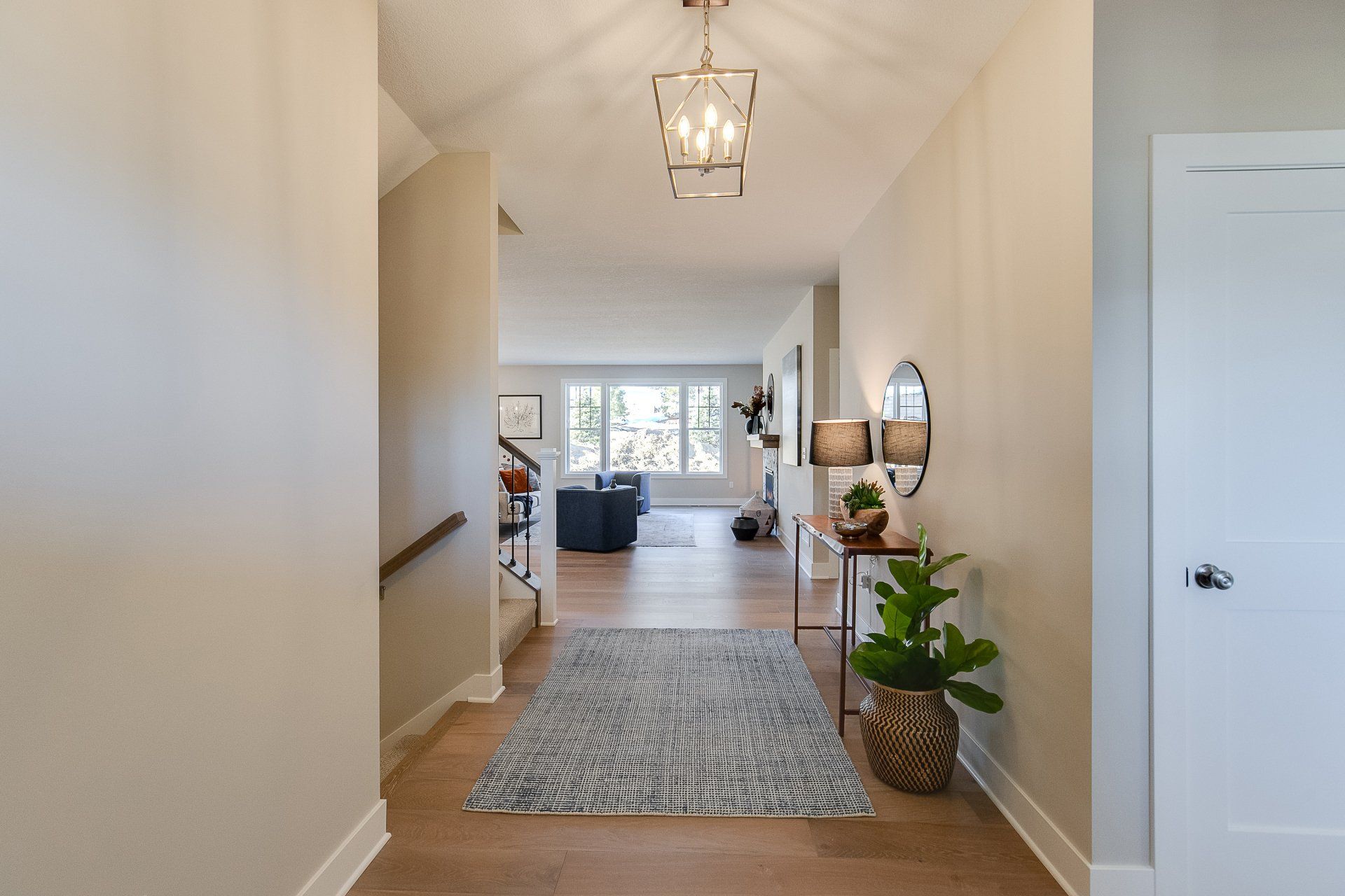 A hallway in a house with a rug on the floor and a chandelier hanging from the ceiling.