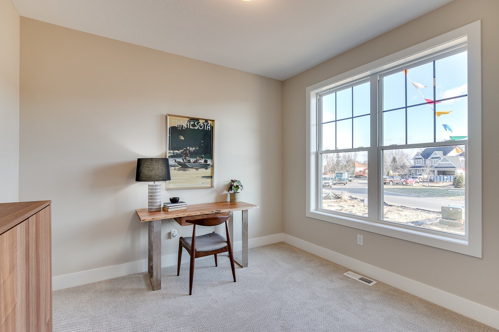 A room with a desk and chair in it and a large window.