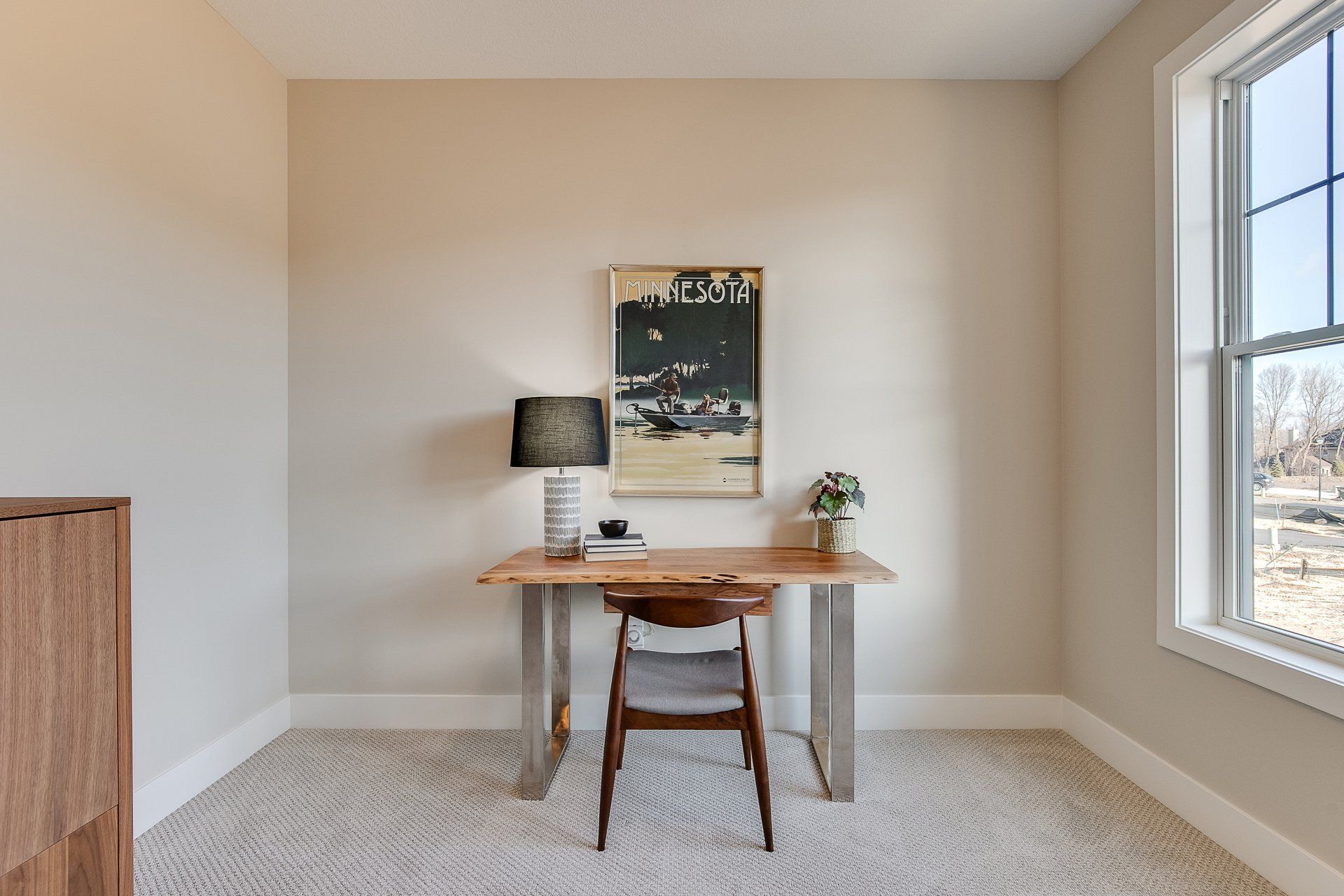 A room with a desk and chair in it and a window.