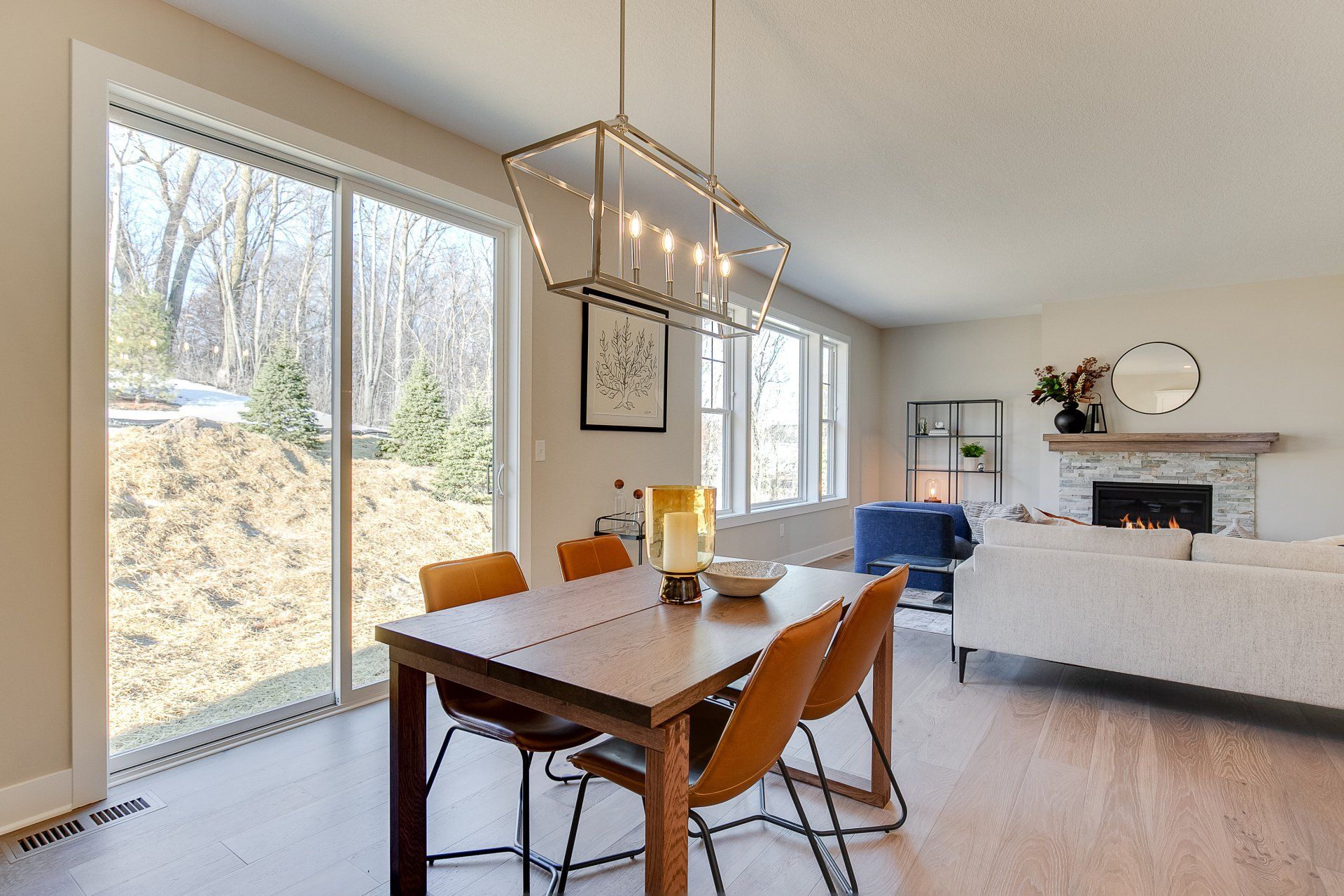 A dining room table and chairs in a living room with sliding glass doors.