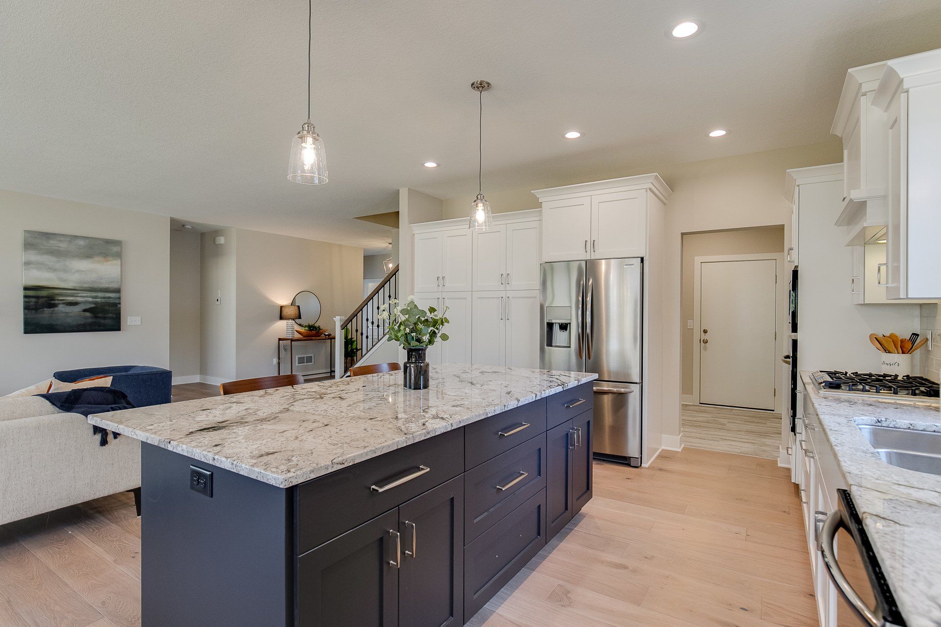 A kitchen with black cabinets, granite countertops, stainless steel appliances, and a large island.