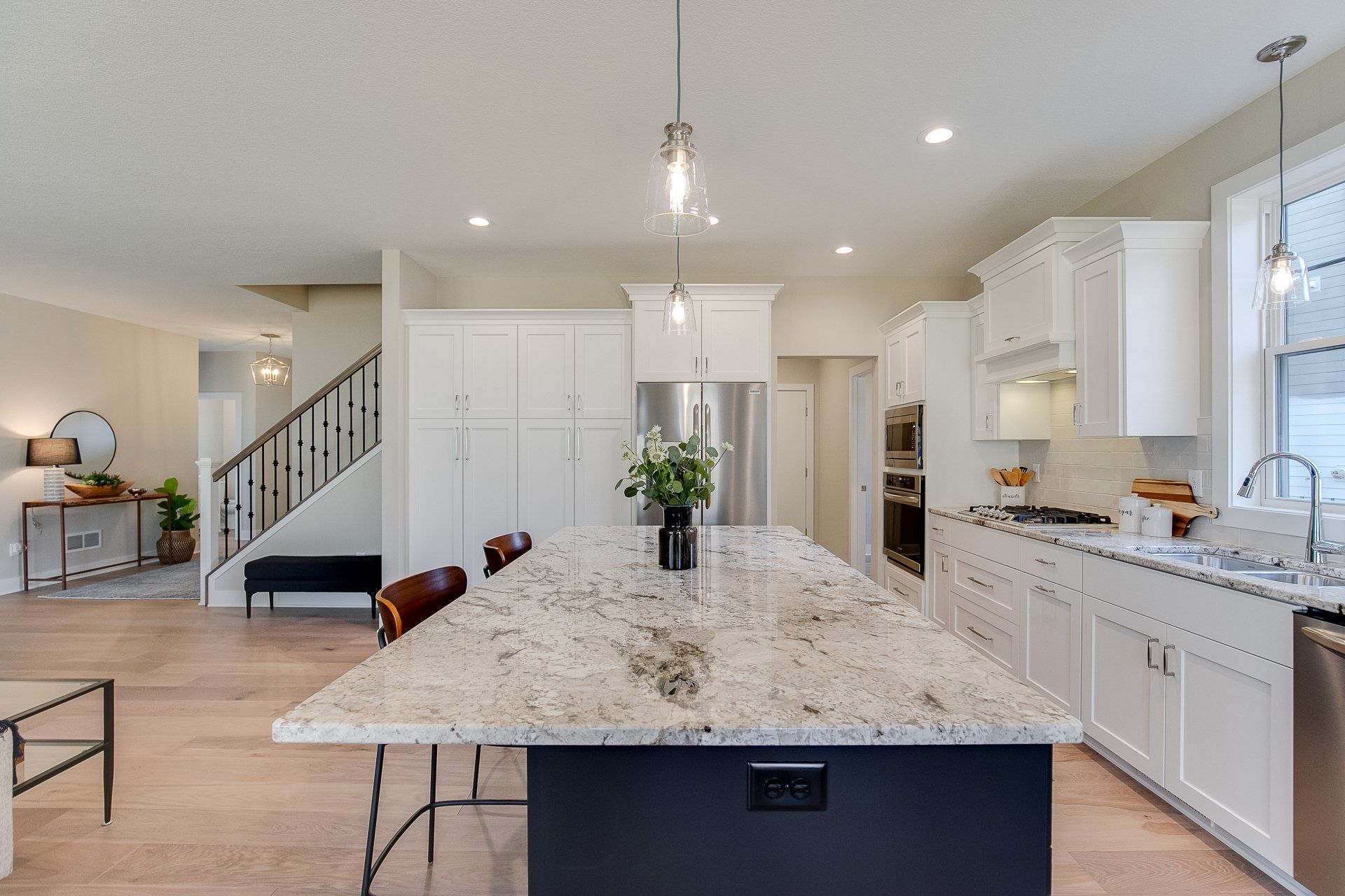 A kitchen with granite countertops, white cabinets, stainless steel appliances, and a large island.