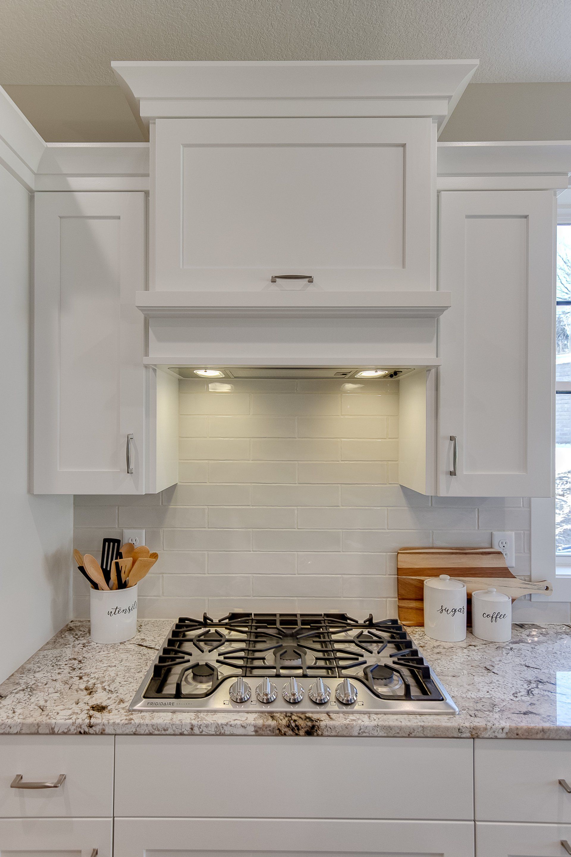 A kitchen with a stove top oven and white cabinets.