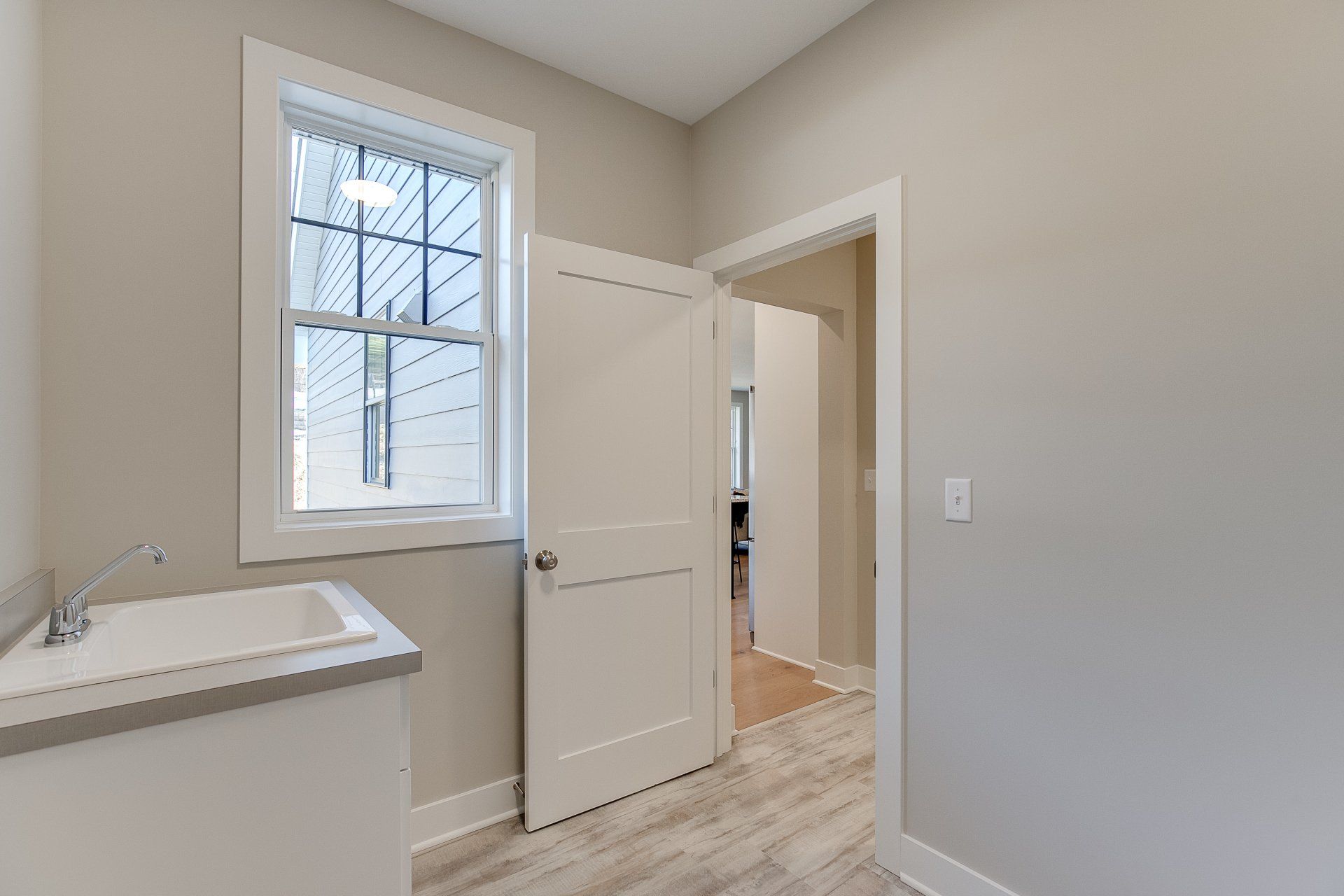 A laundry room with a sink and a window.