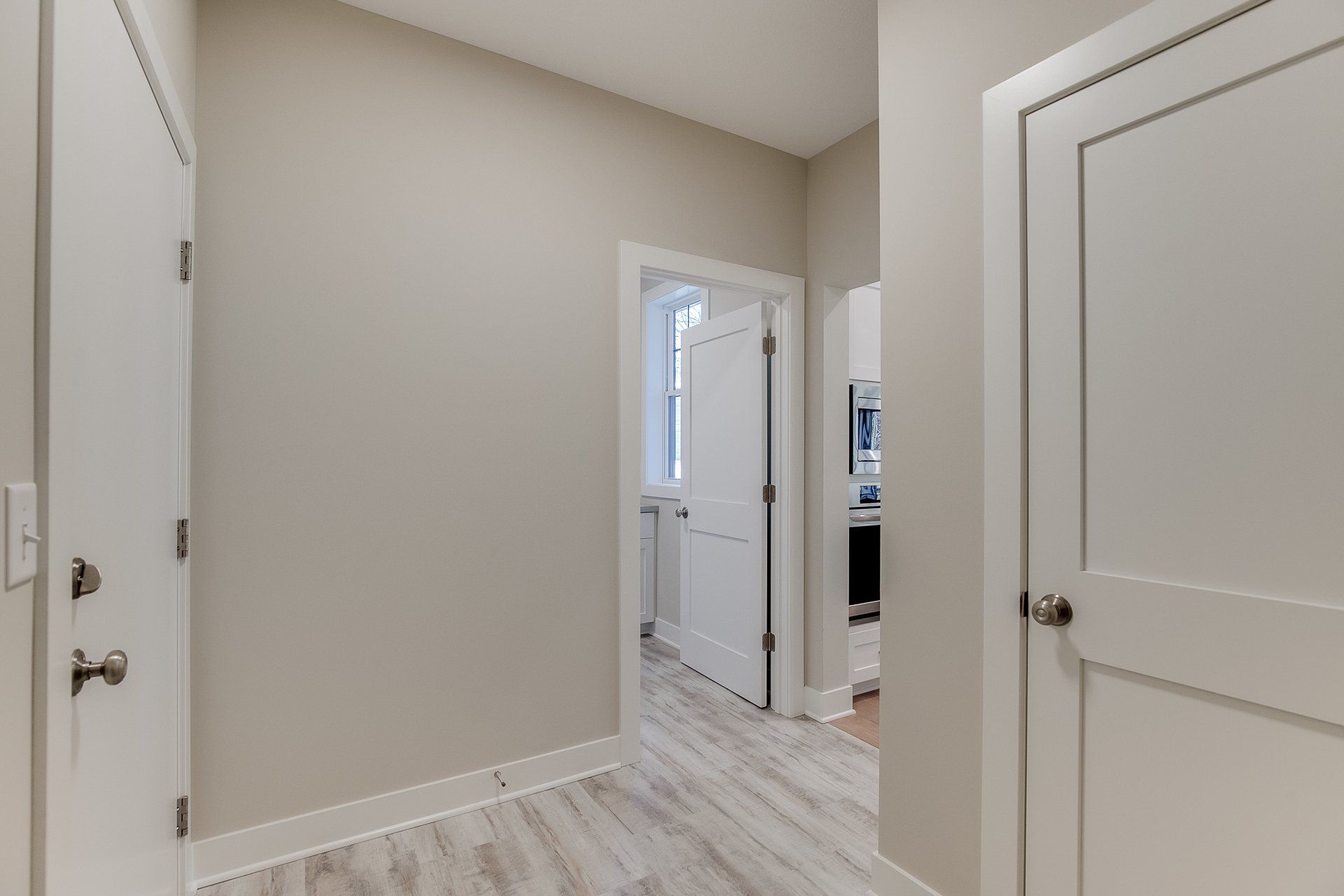 A hallway in a house with white doors and a wooden floor.