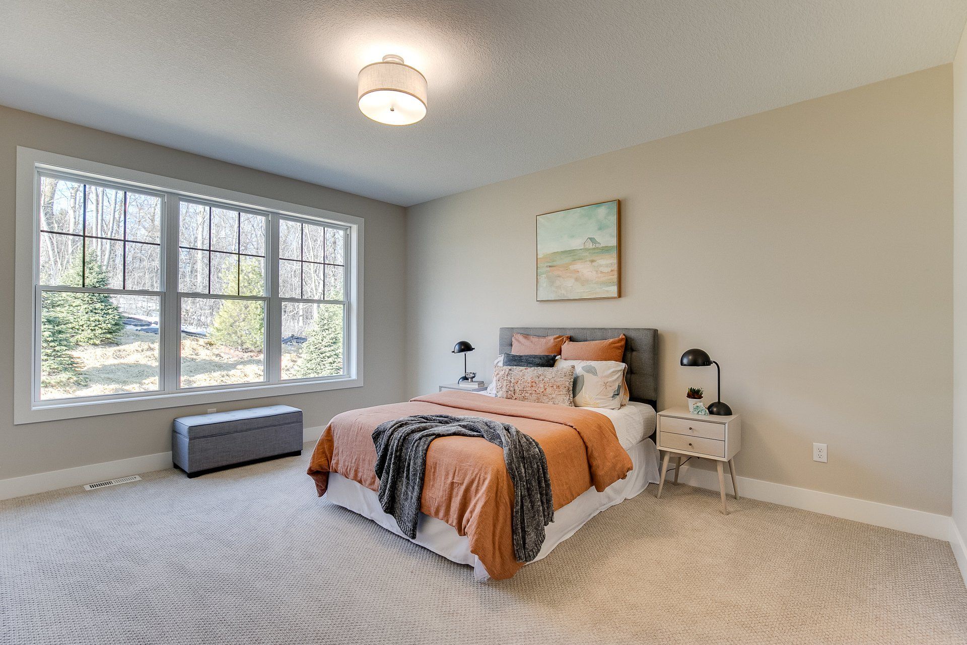 A bedroom with a large bed, two windows, and a bench.