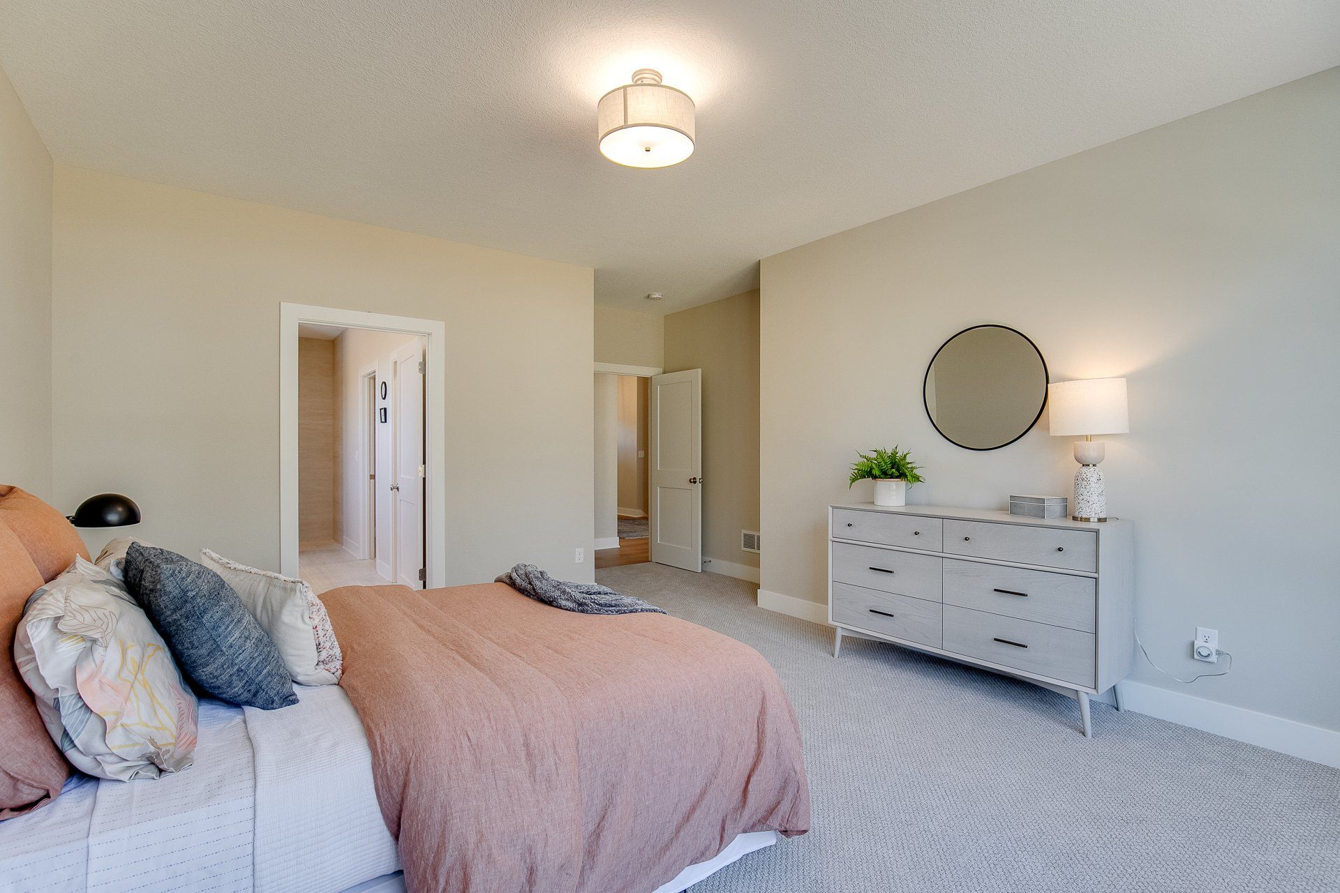 A bedroom with a bed, dresser, and mirror.