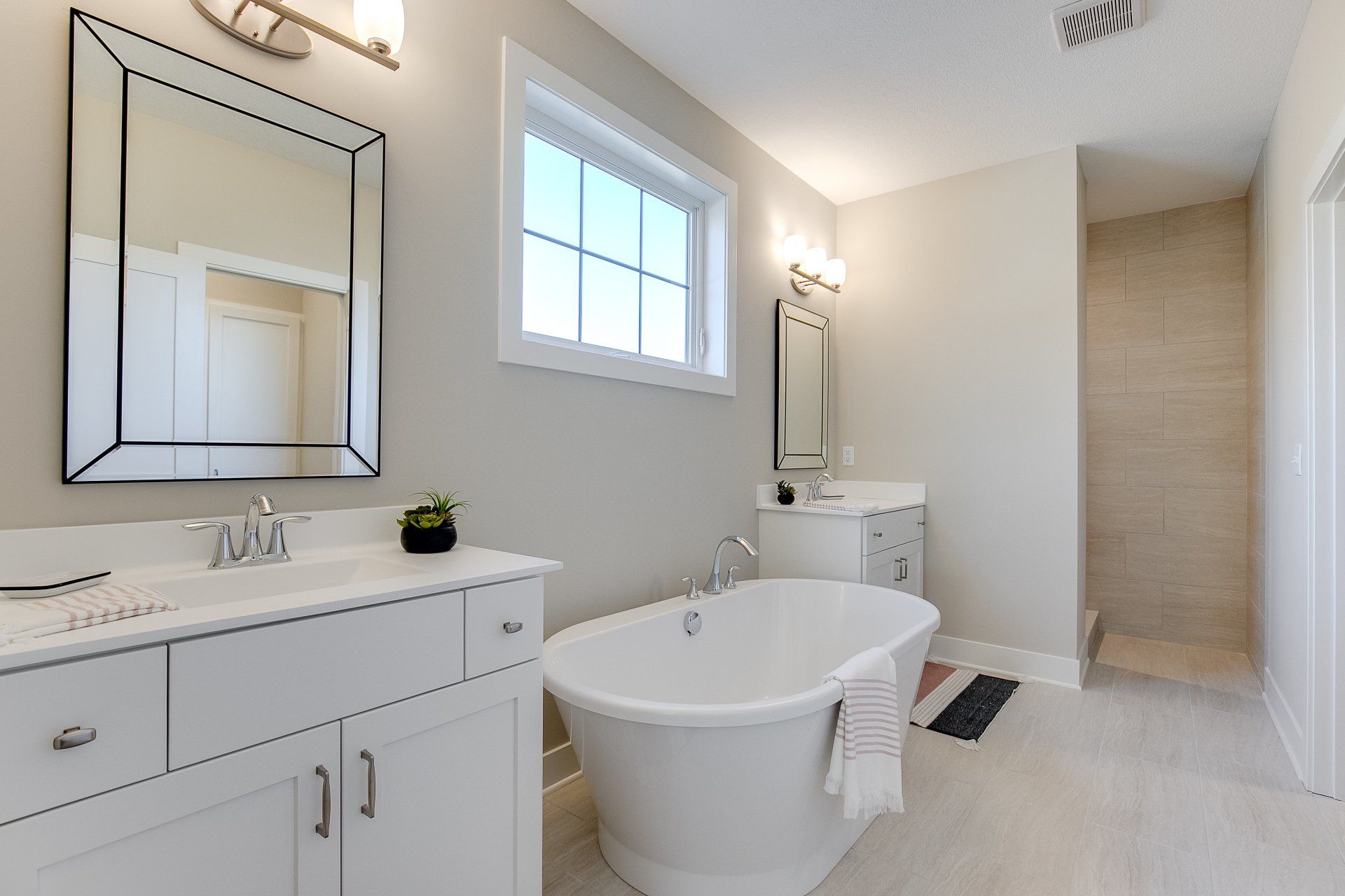 A bathroom with a tub, sink, mirror, and window.