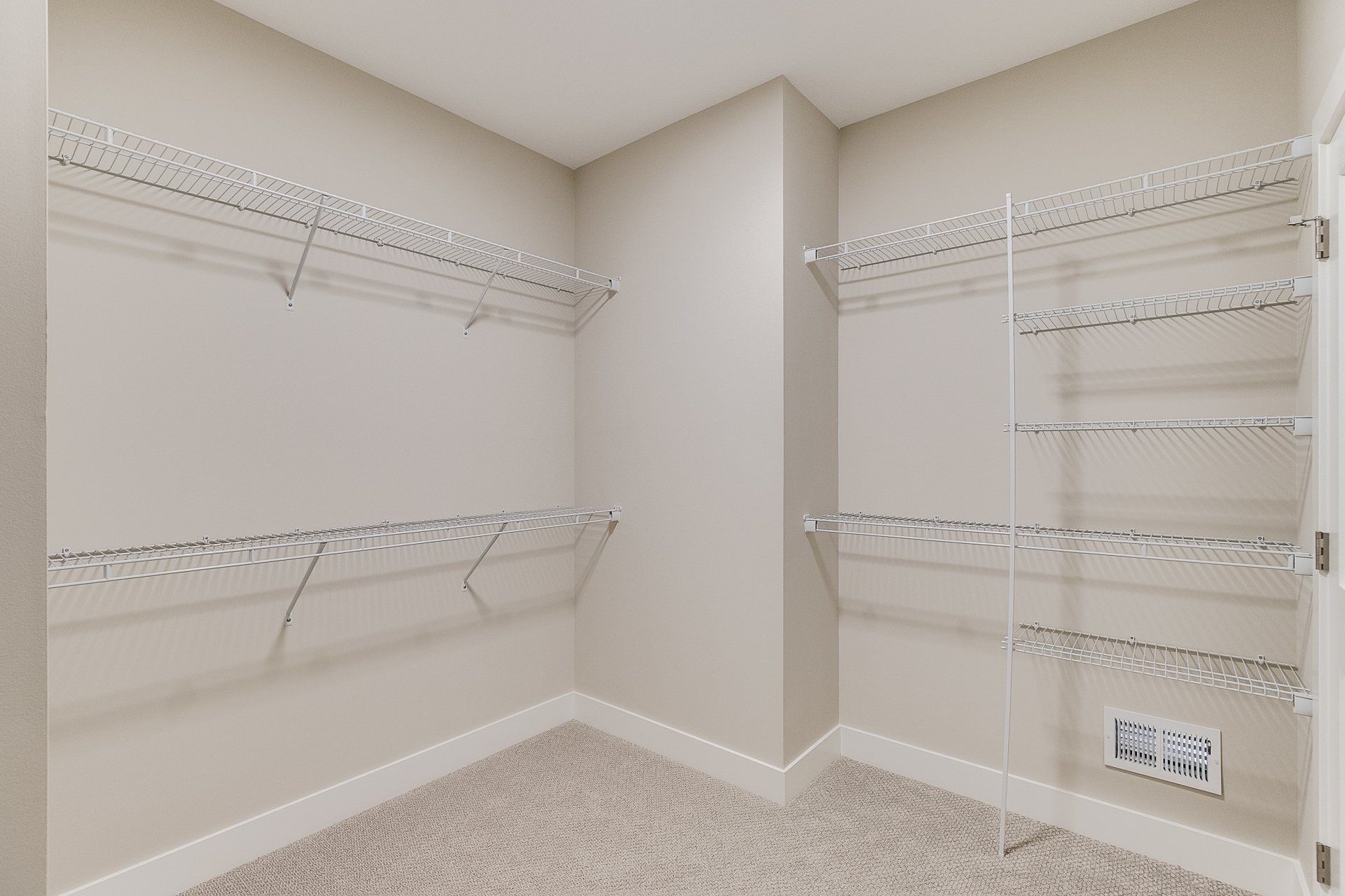 A walk in closet with lots of shelves and a carpeted floor.