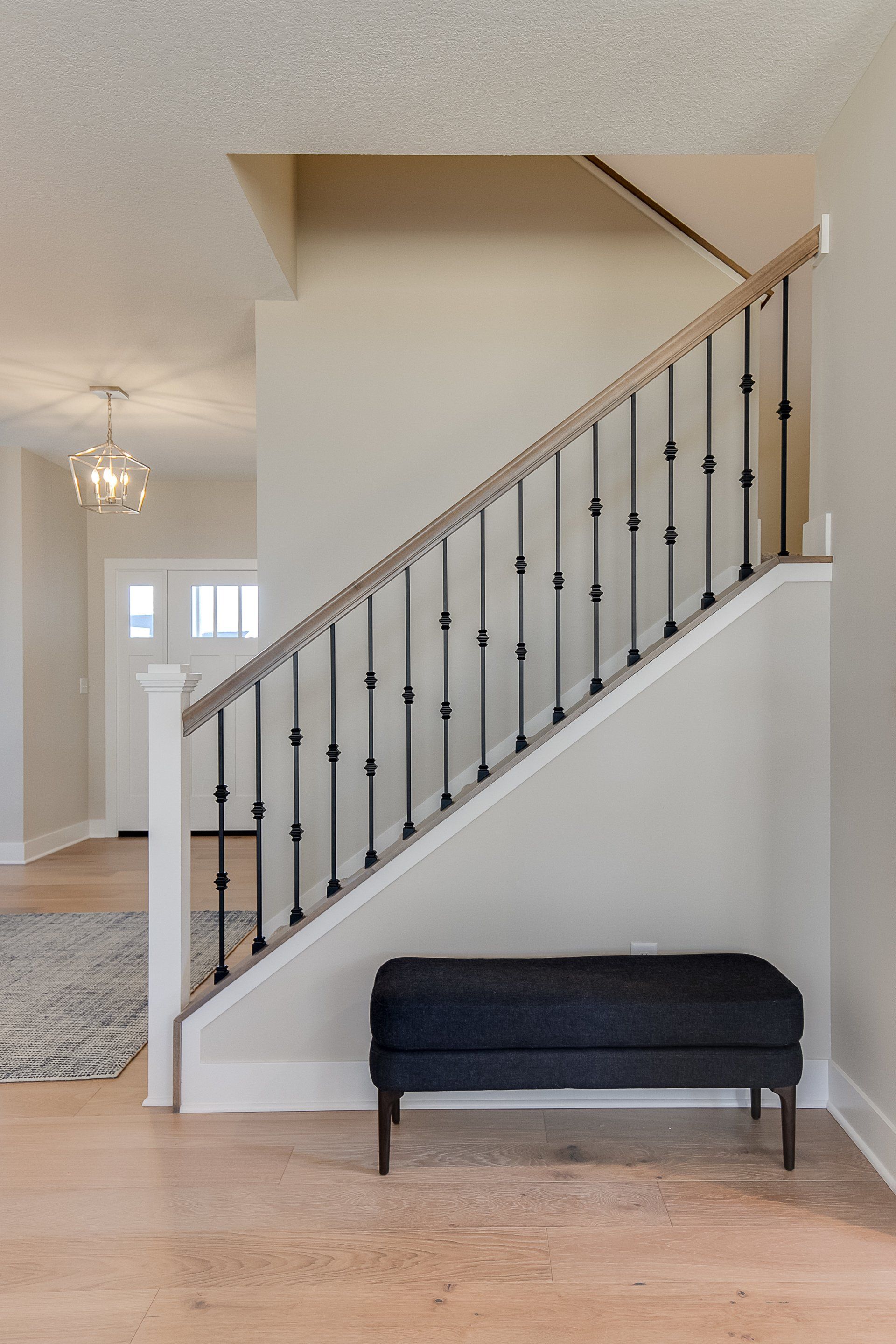 There is a bench under the stairs in the hallway.