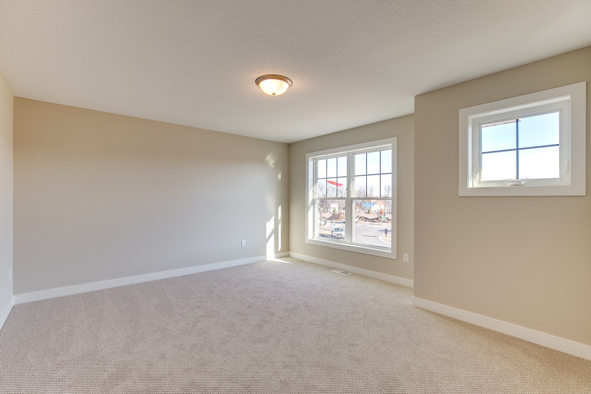 An empty room with a carpeted floor and two windows.