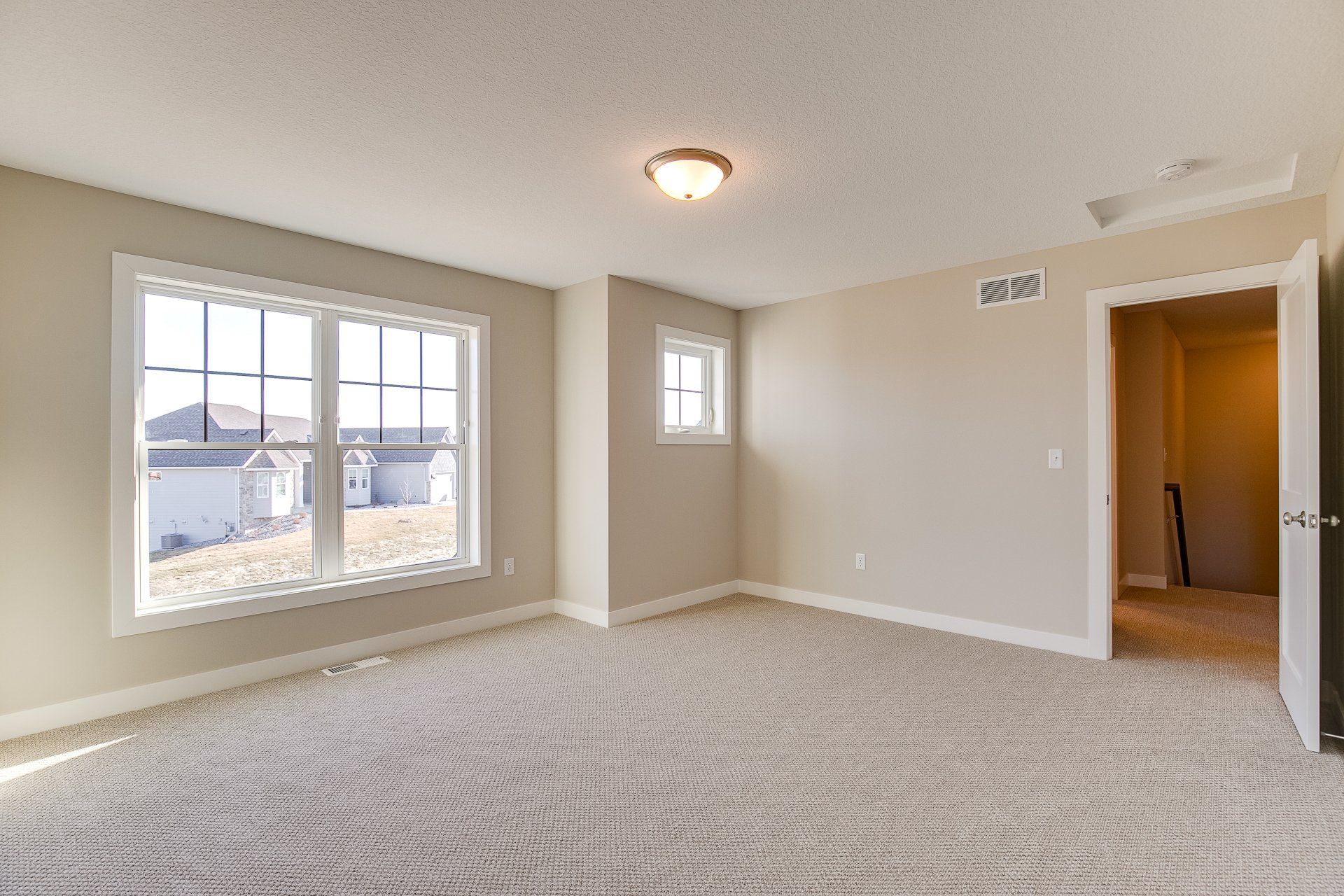 A large empty room with a lot of windows and a carpeted floor.
