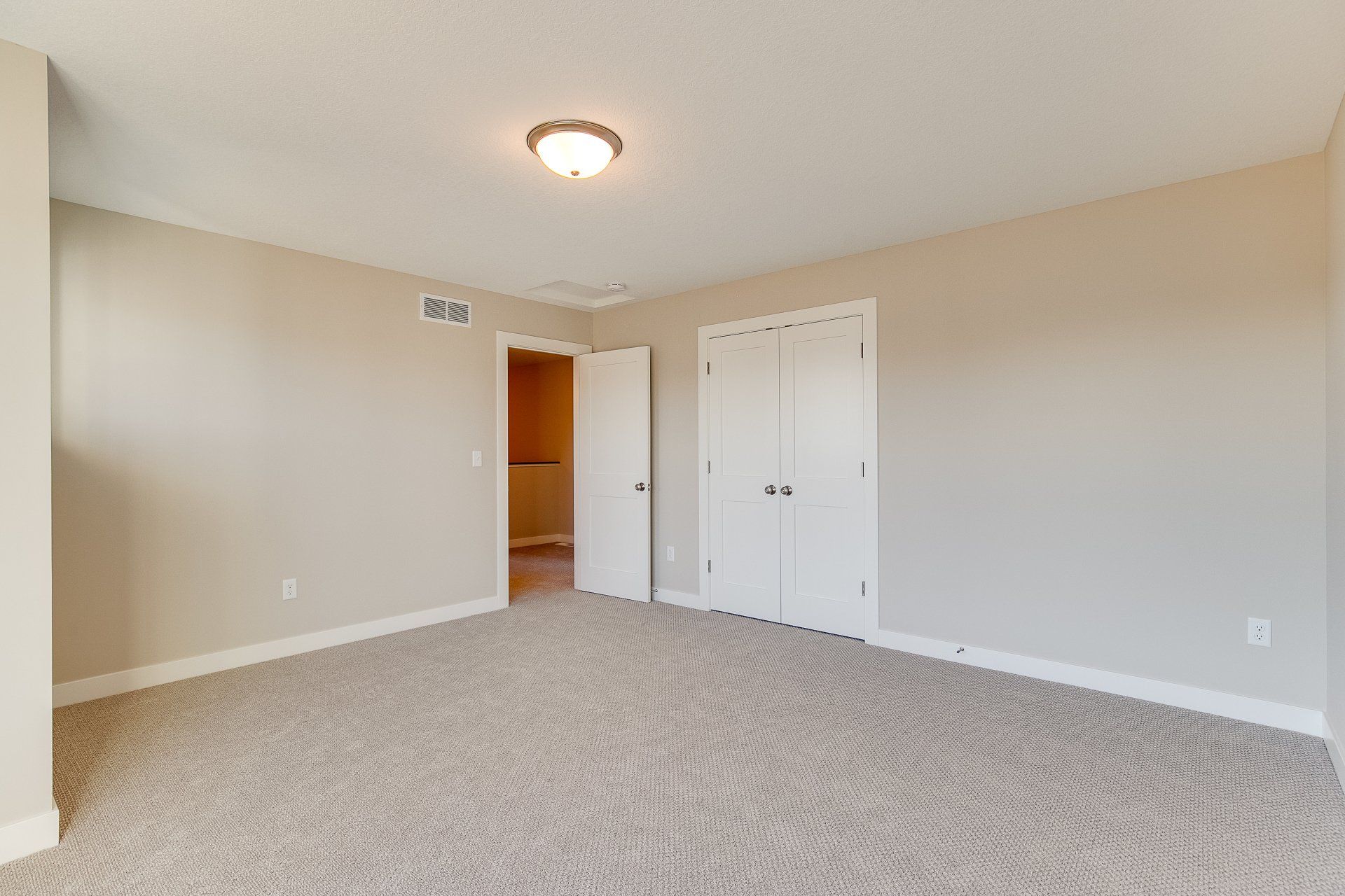 An empty bedroom with a carpeted floor and a closet.