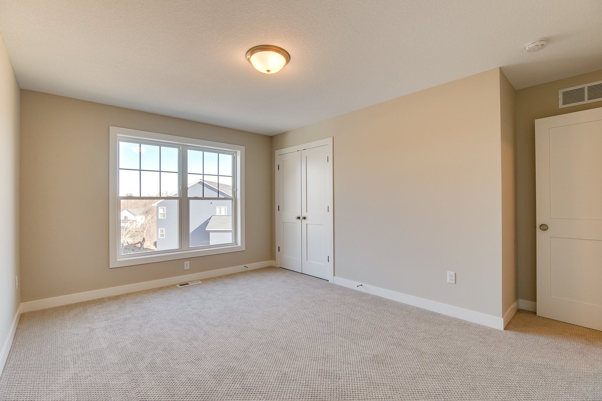 An empty bedroom with a large window and a closet.