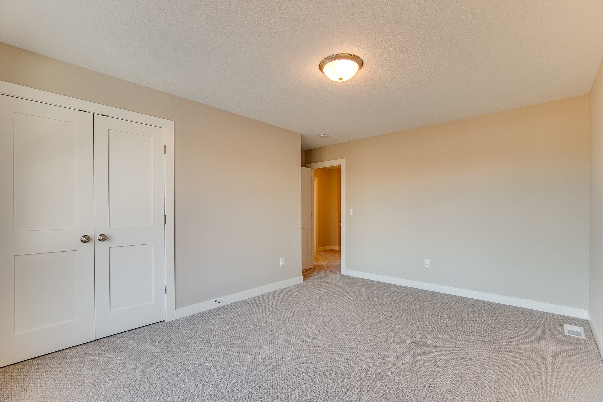 An empty bedroom with a carpeted floor and white walls.