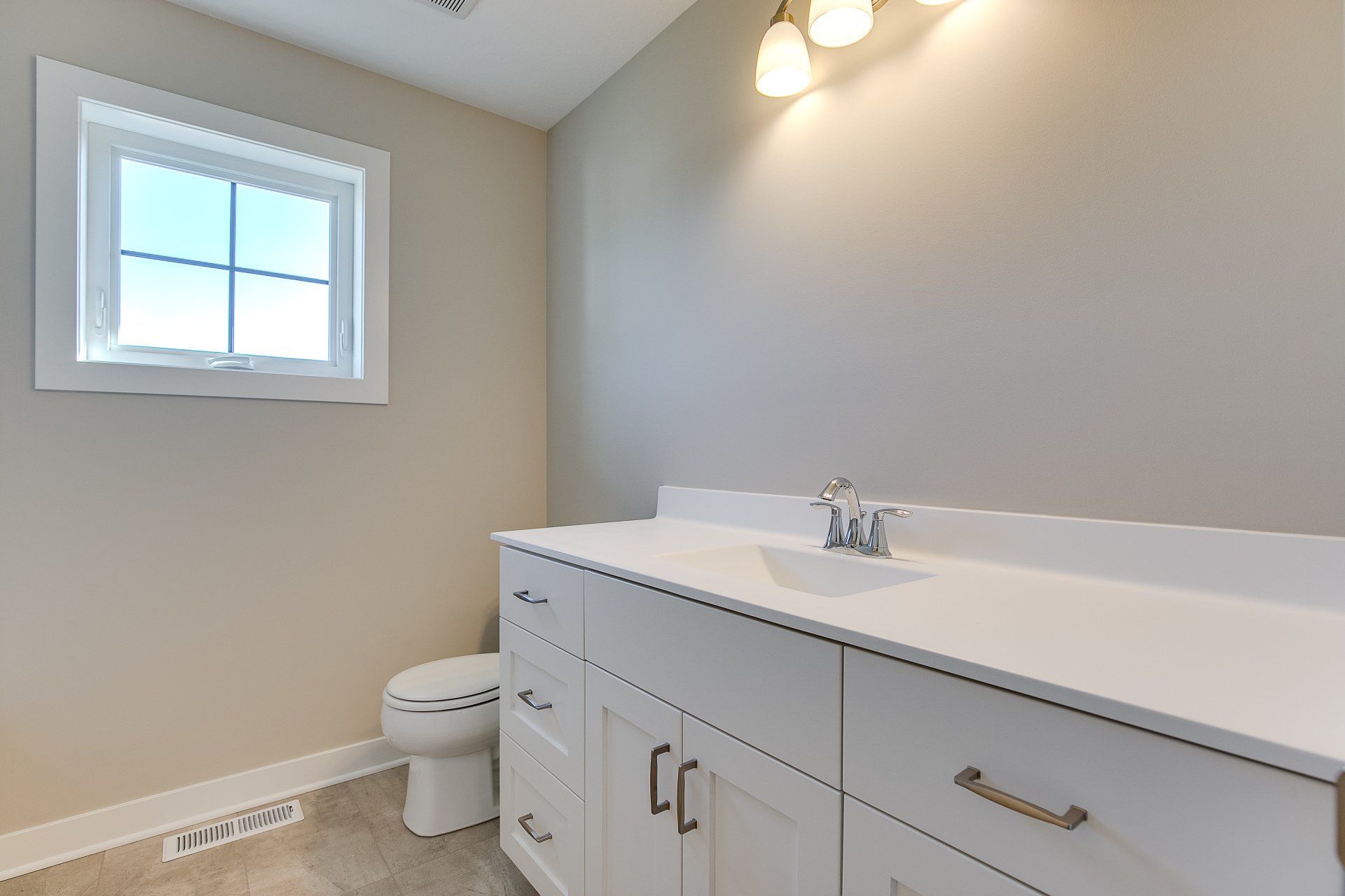 A bathroom with a sink, toilet, and window.