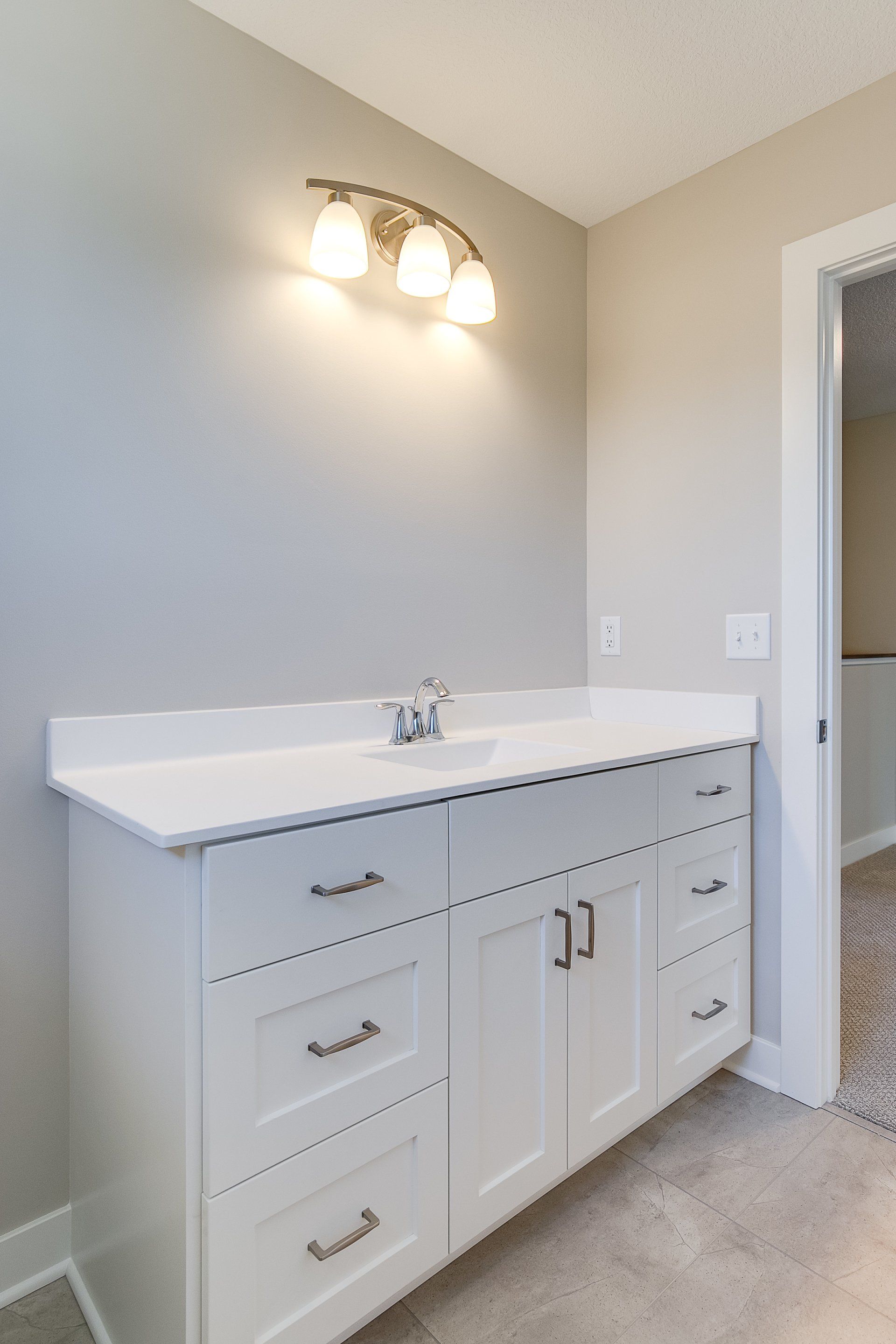 A bathroom vanity with a sink and a light on the wall.