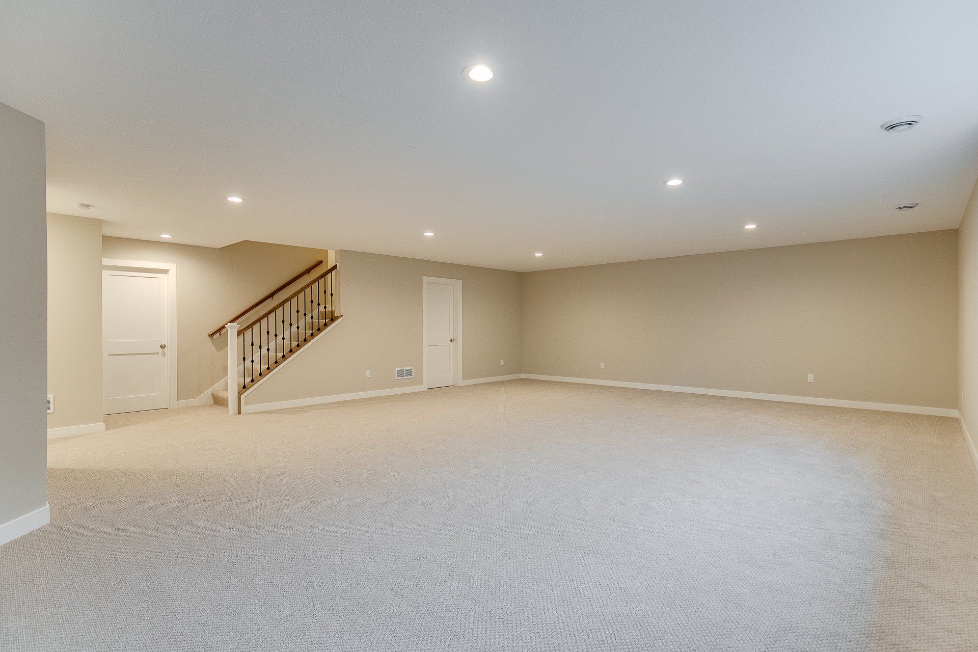 An empty basement with a staircase leading up to the second floor.