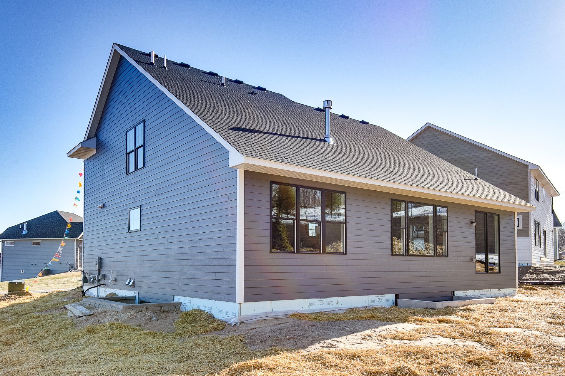 A large house with a lot of windows is sitting on top of a grassy hill.