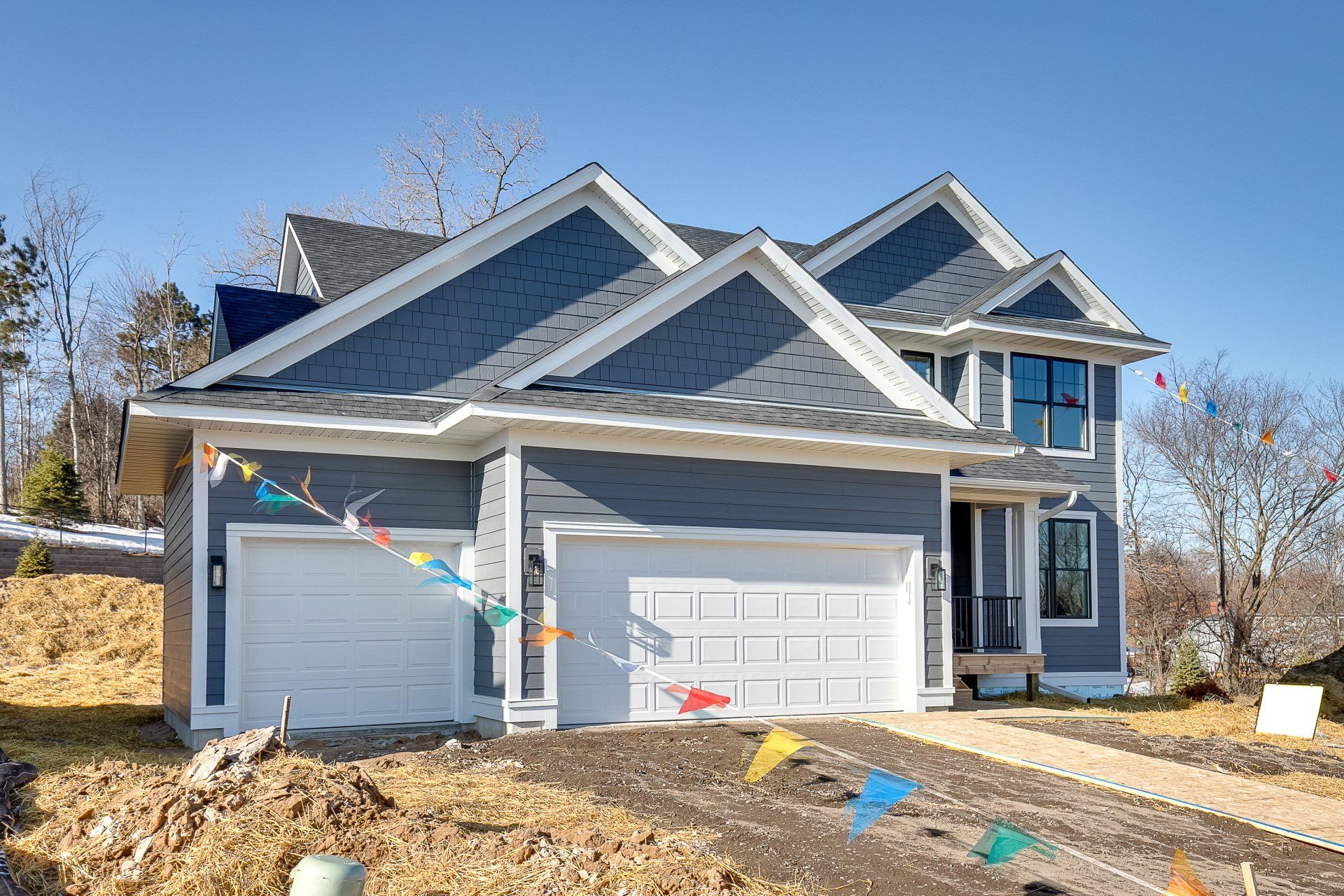 A large house with two garage doors is sitting on top of a dirt hill.