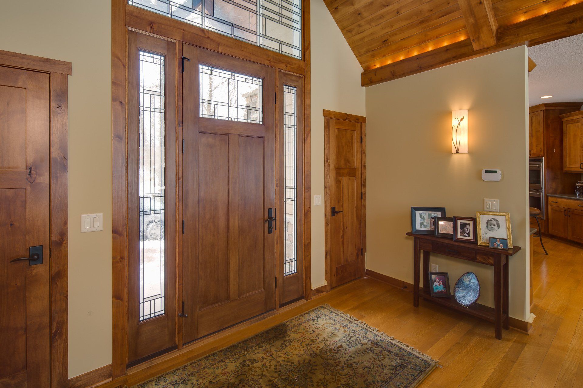 A hallway in a house with wooden doors and a table with pictures on it.