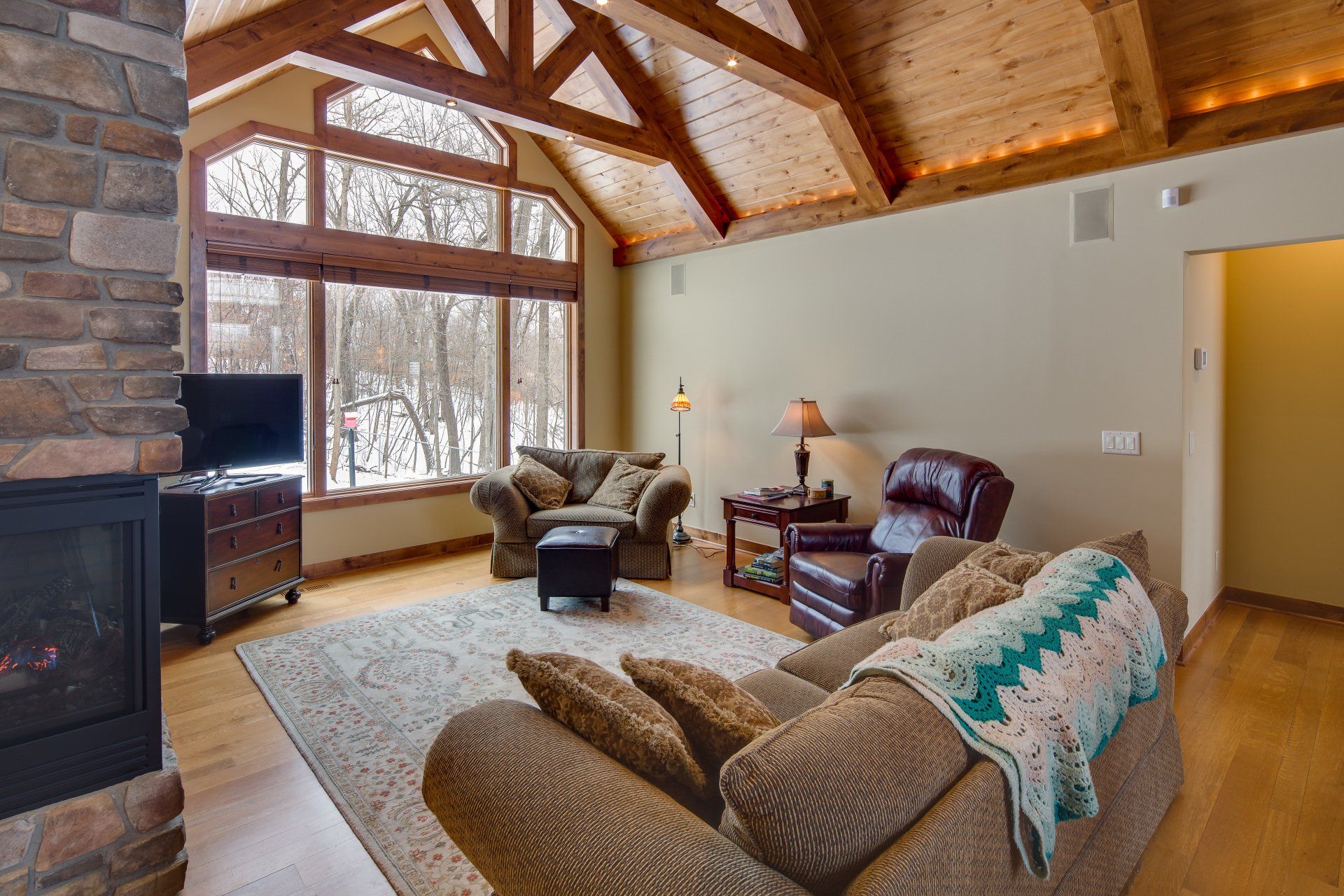 A living room with a couch , chairs , television and fireplace.