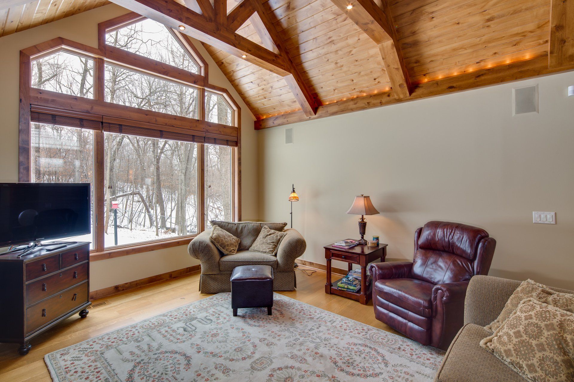 A living room with a couch , two chairs , a television and a large window.