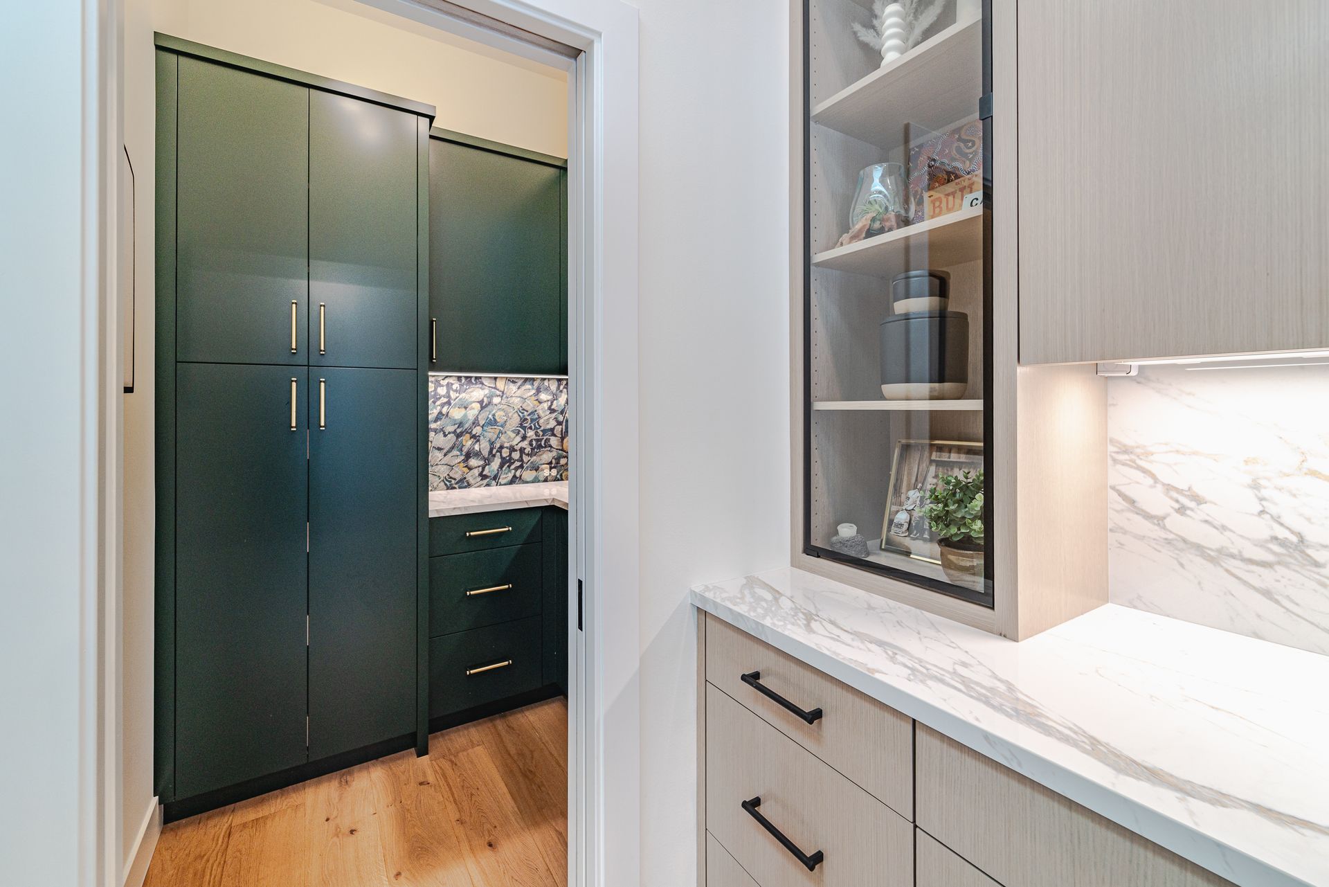 A kitchen with green cabinets and a glass door leading to a pantry.