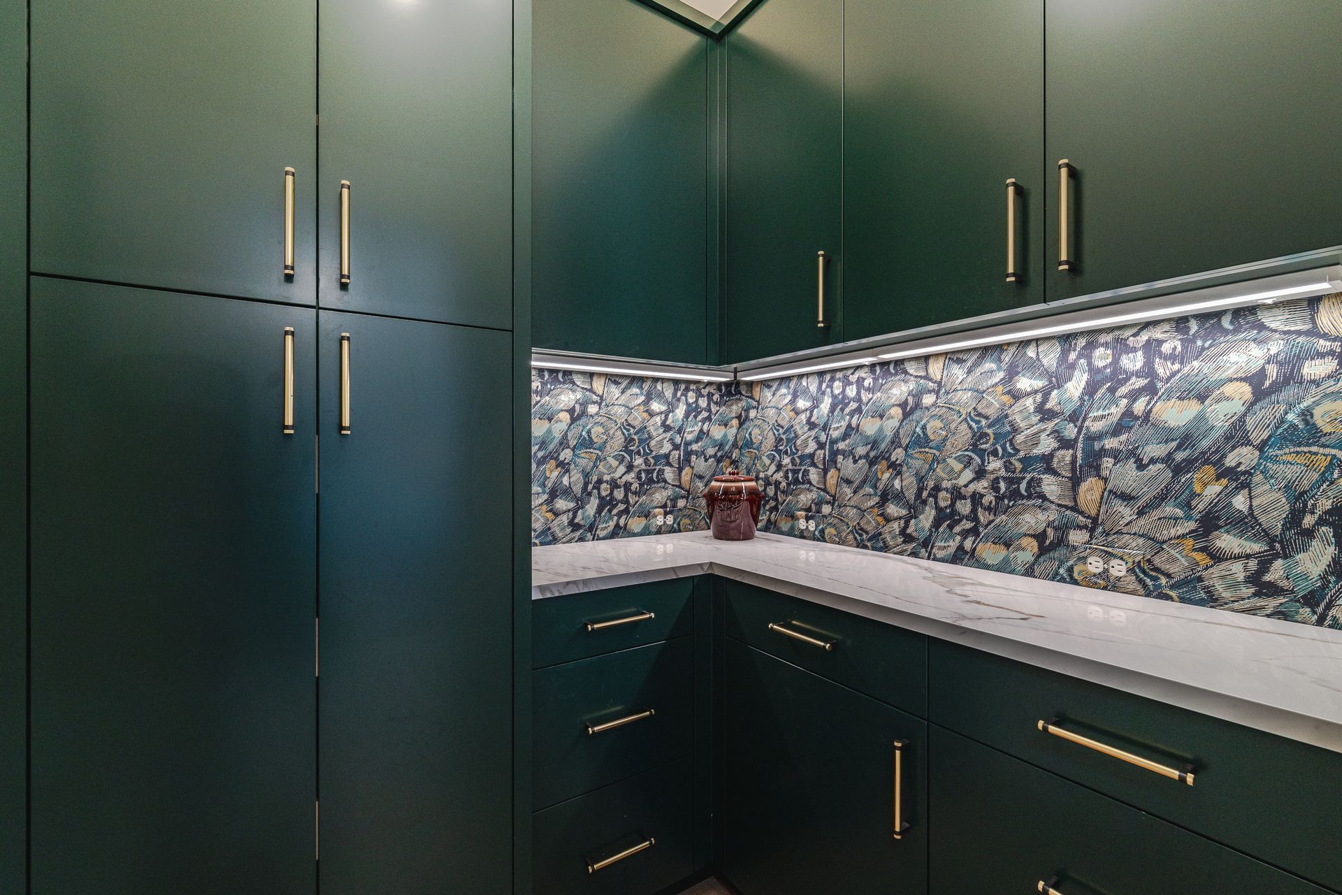 A kitchen with green cabinets and white countertops.