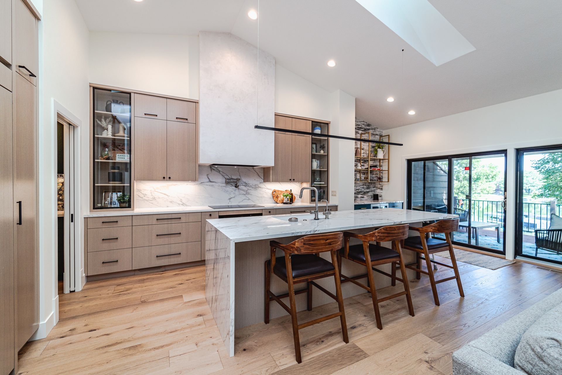 A kitchen with a large island and stools in a house.