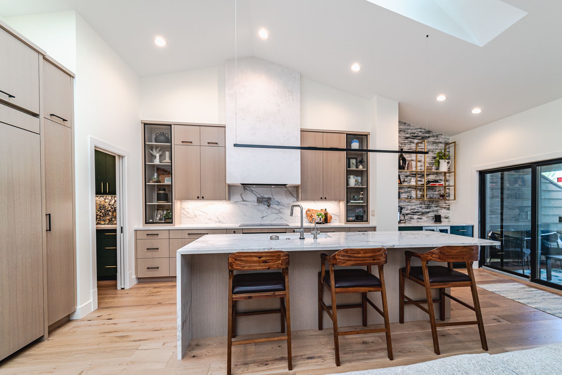 A kitchen with a large island and stools in it.
