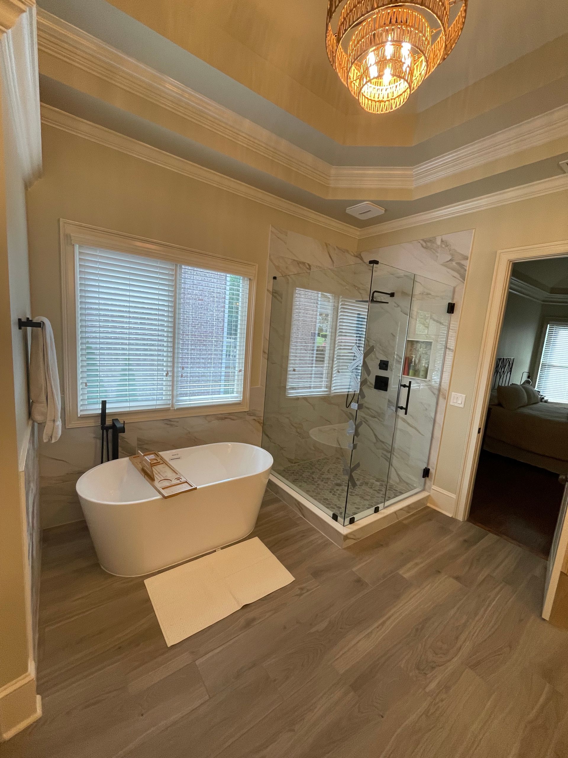 Elegant bathroom with a freestanding tub, glass shower, and wood-look tile flooring.