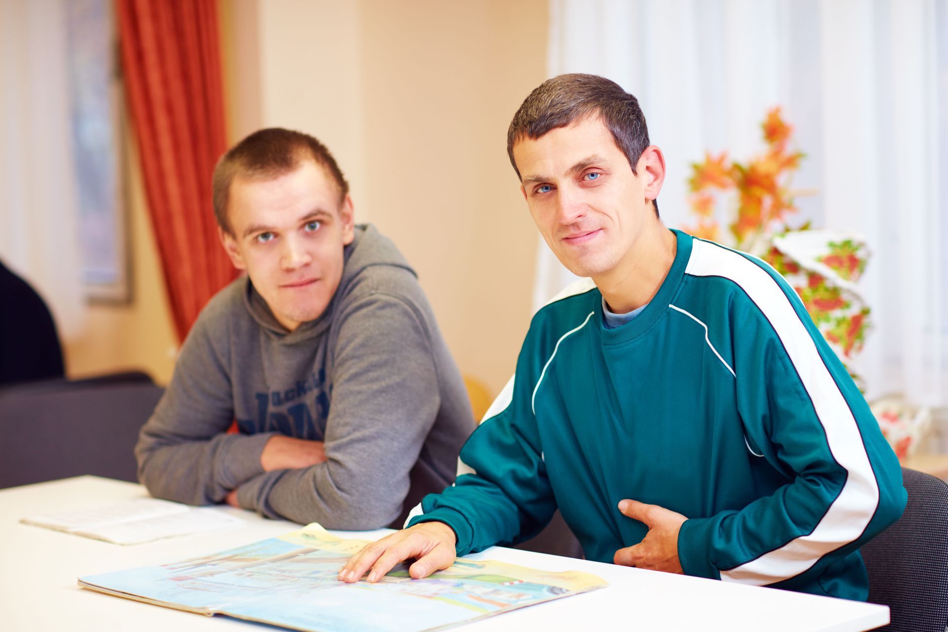 Two young men are sitting at a table looking at a map.