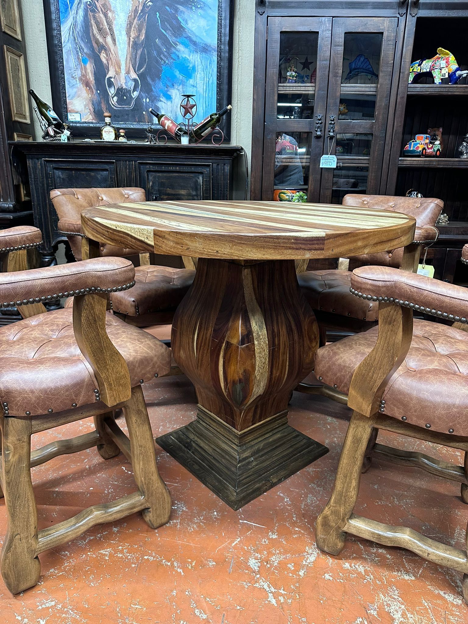 Rustic dining set with a wooden hexagonal table and leather chairs. The table has a decorative base and a patterned top.