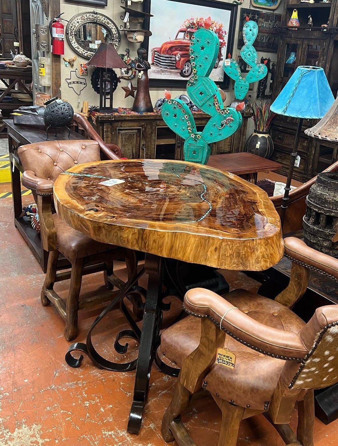 A small round table with two brown leather chairs in a shop. The table has a dark, glossy top and a black metal base.