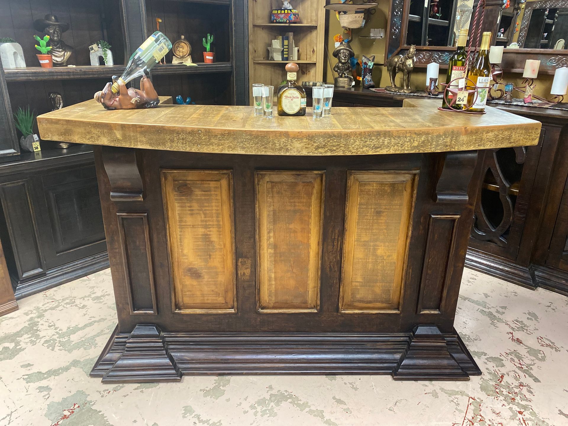 Wooden bar with a stone countertop, brown panels, and liquor bottles.