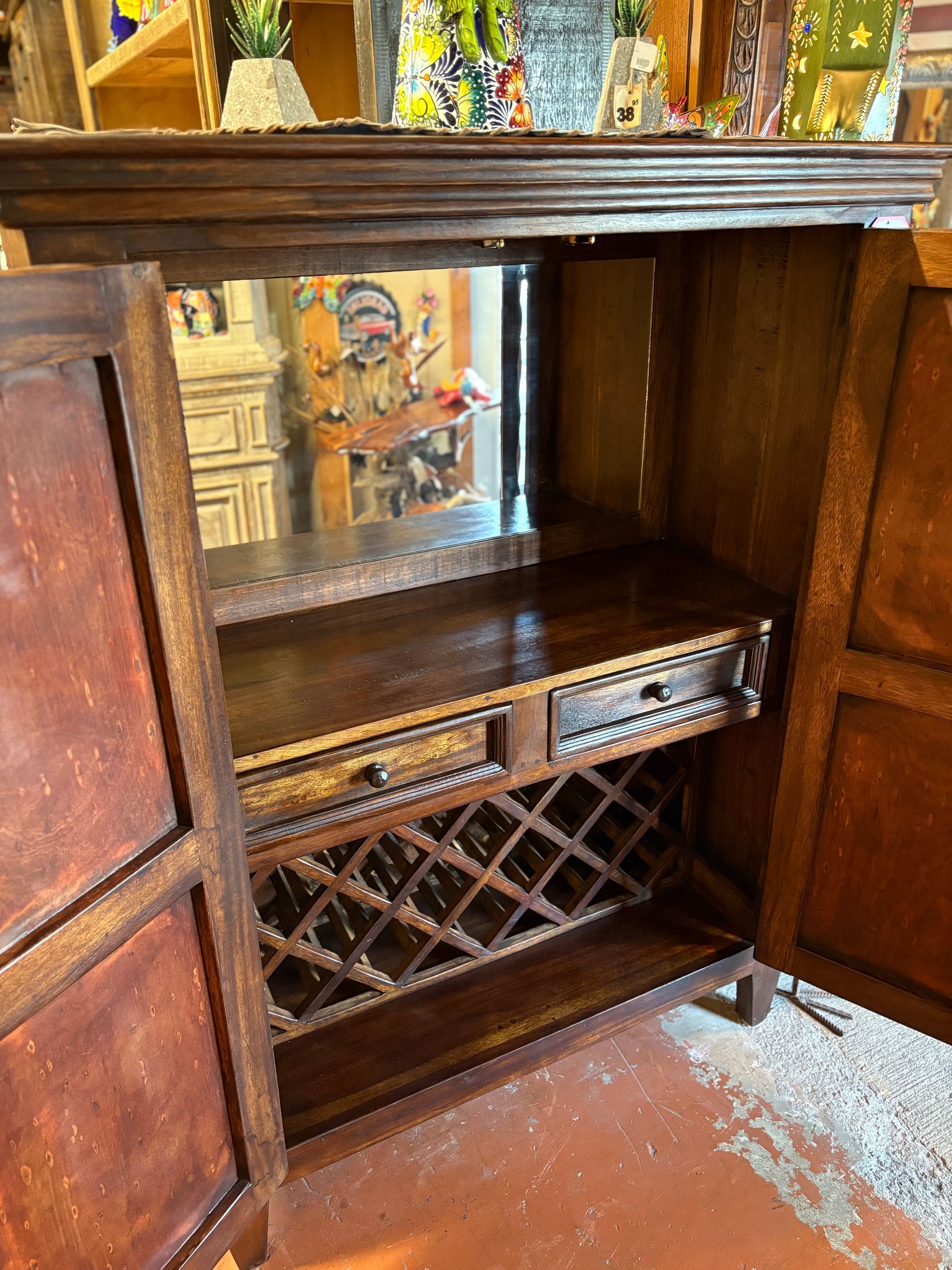 Wooden bar cabinet with open doors, revealing a shelf, wine rack, and two drawers, with a mirror in the back.