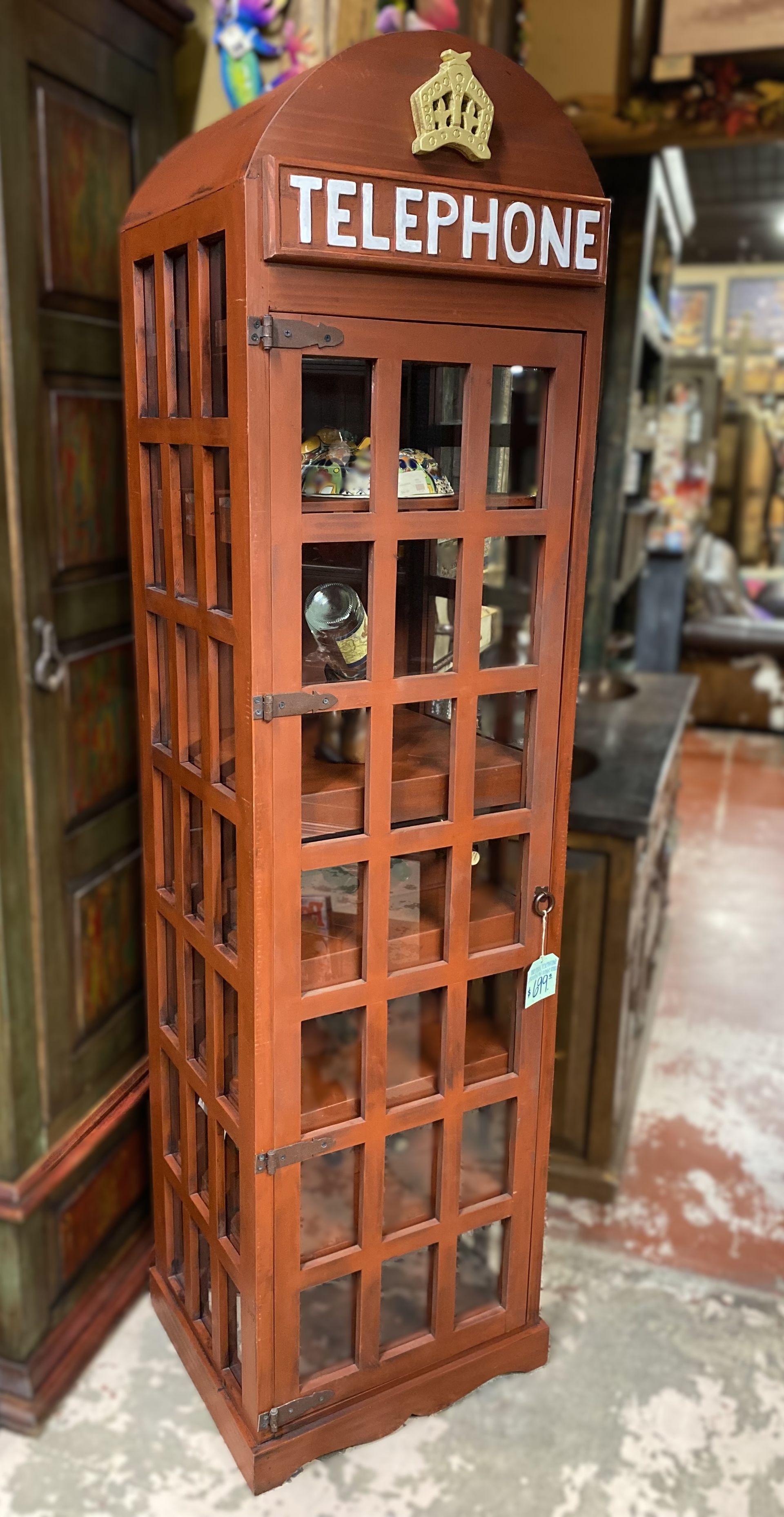 A wooden telephone booth-shaped cabinet, painted dark red, with 