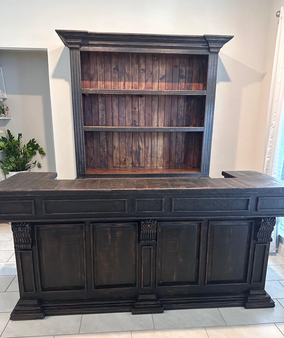 Dark wooden bar with a matching hutch. The bar has carved details and shelves in the hutch.