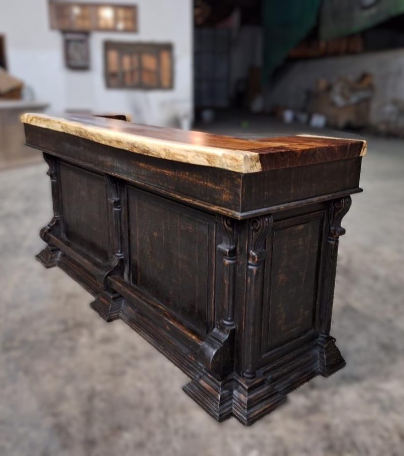 A dark stained wooden bar with a light colored countertop. Ornate detailing on the front panels and base.