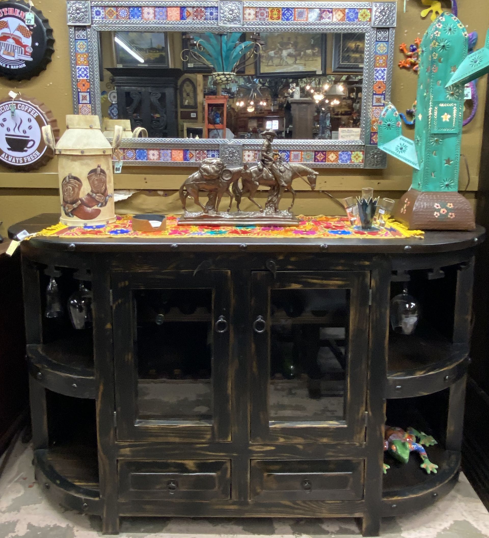 Dark wood sideboard with a mirror, decor, and glass racks. The sideboard has a distressed finish and glass doors.