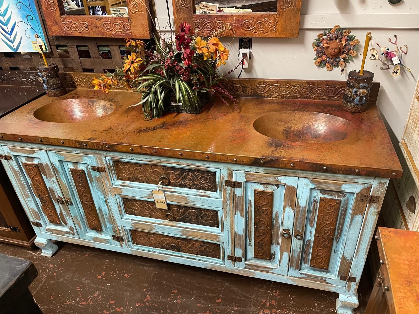 Rustic double bathroom vanity with copper sinks, copper countertops, and distressed teal cabinetry.