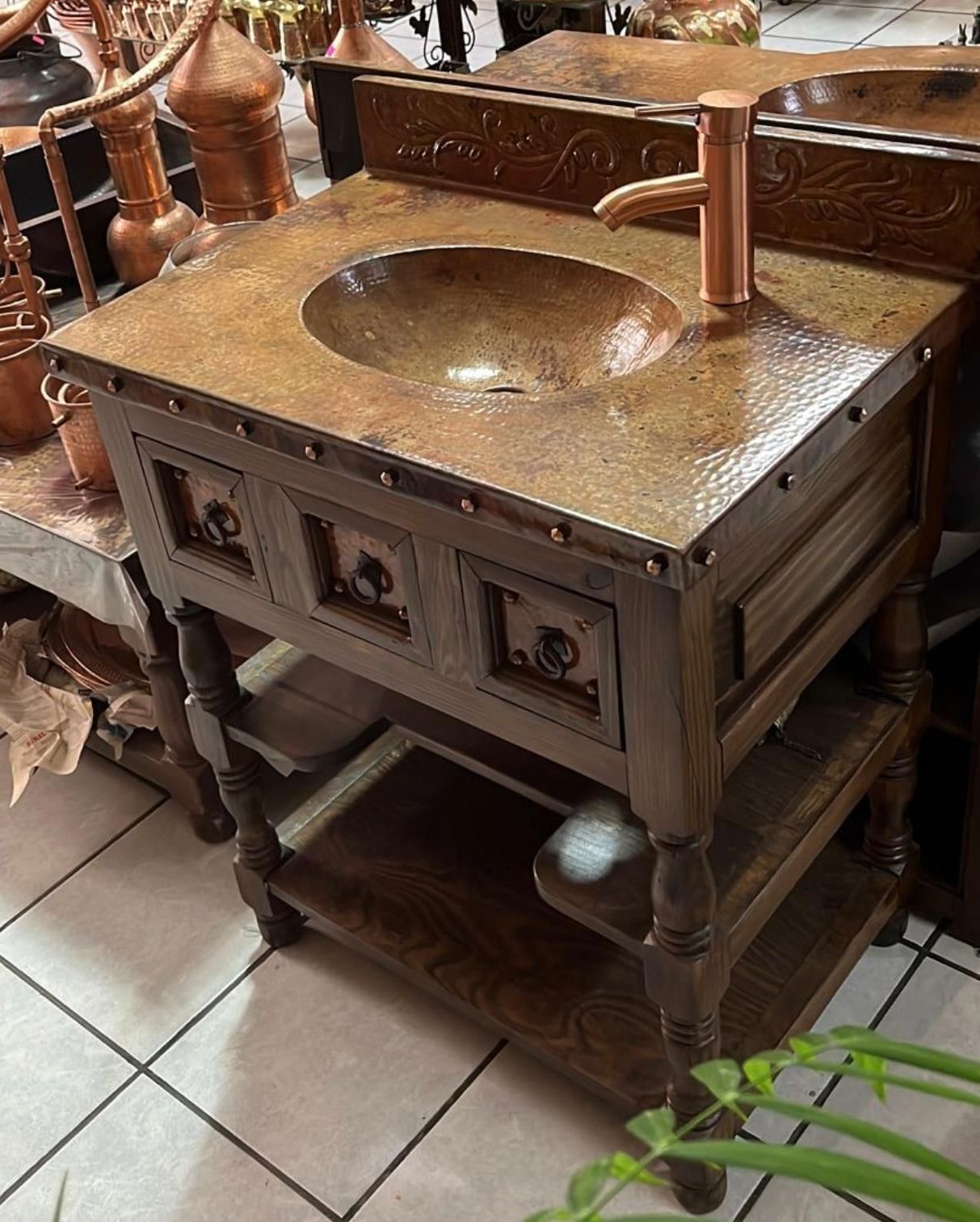 Copper sink vanity with a hammered copper top, a wooden frame, and a copper faucet.