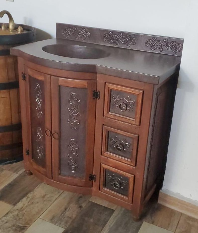 Wooden bathroom vanity with a copper sink, countertop, and decorative panels. The cabinet has two doors and three drawers.